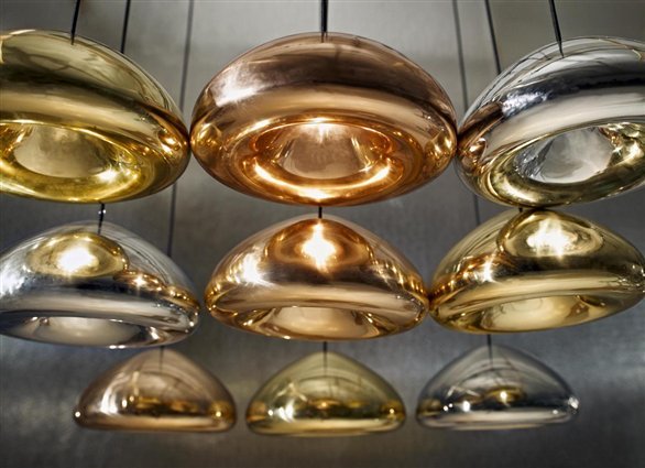 Nahaufnahme von mehreren Tom Dixon Void Pendelleuchten in Gold, Kupfer und Silber.