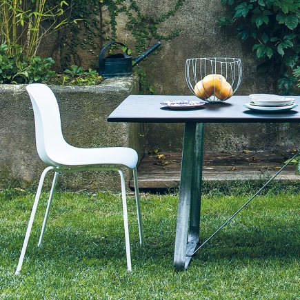 Weißer Troy Chair Stuhl mit vier Beinen von Magis neben einem Gartentisch auf Rasen.