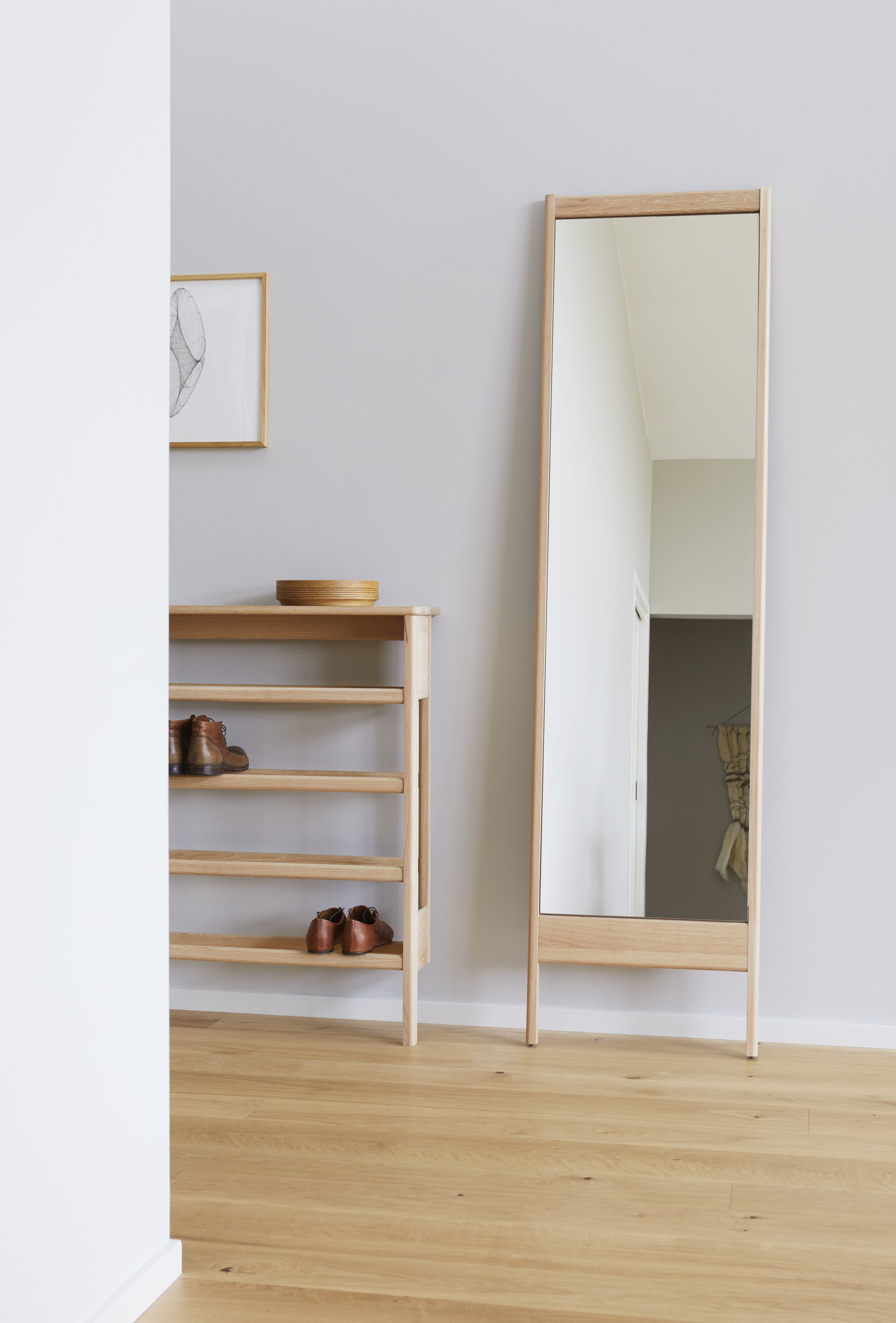 A Line Schuhregal aus geölter Eiche mit Schuhen und passendem Spiegel im Flur.