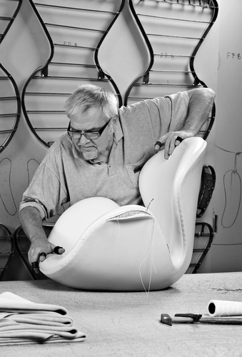 Handwerker fertigt einen weißen Schwan Sessel von Fritz Hansen in Handarbeit, Detailaufnahme.