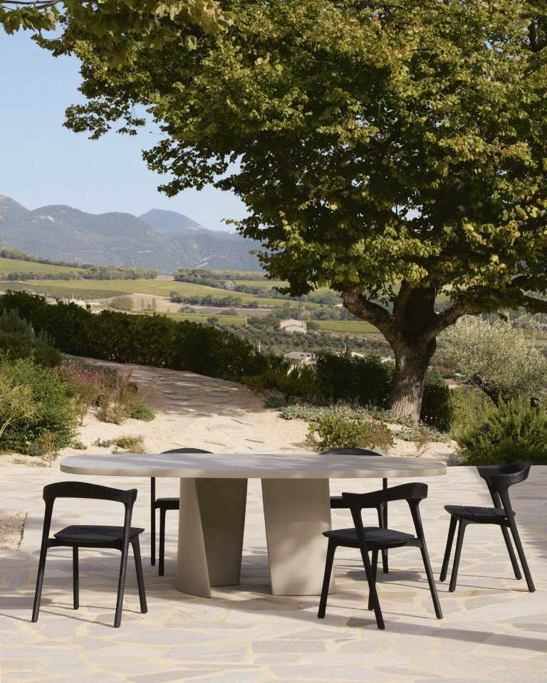 Canyon Outdoor Esstisch von Ethnicraft aus Beton mit Stühlen im Garten, Landschaft im Hintergrund.