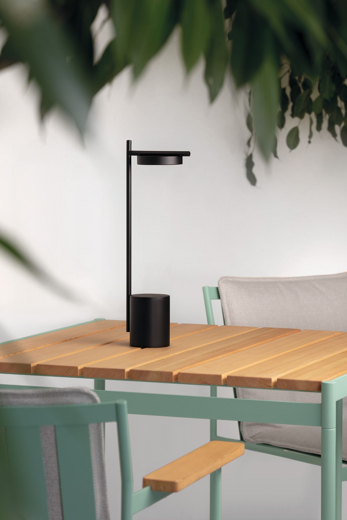 Schwarze Igram Tischleuchte von Grupa auf Holztisch, moderne Akku-Leuchte für drinnen und draußen.