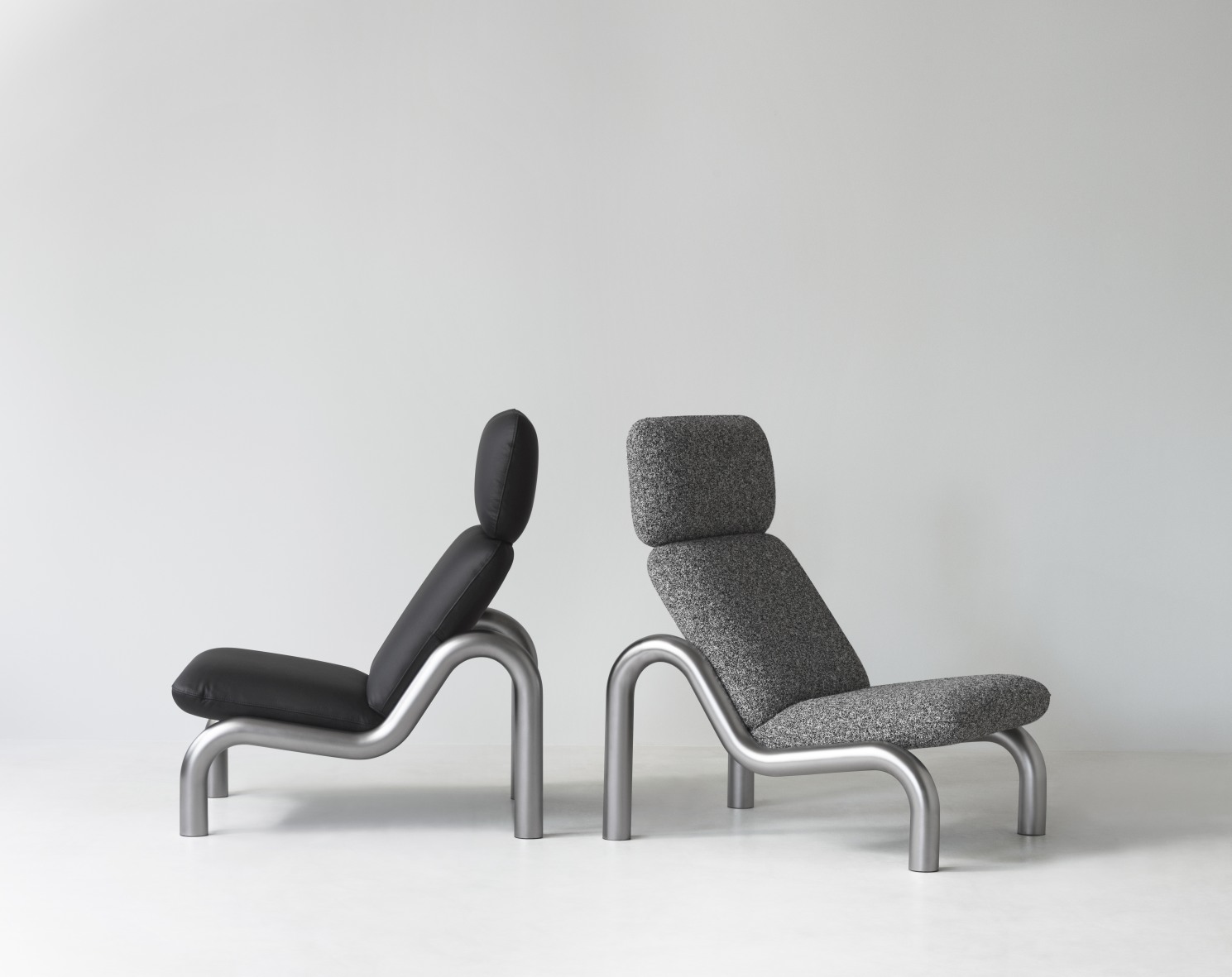 Zwei Tube Lounge Sessel von Normann Copenhagen, einer in Schwarzleder, einer in grauem Stoff.