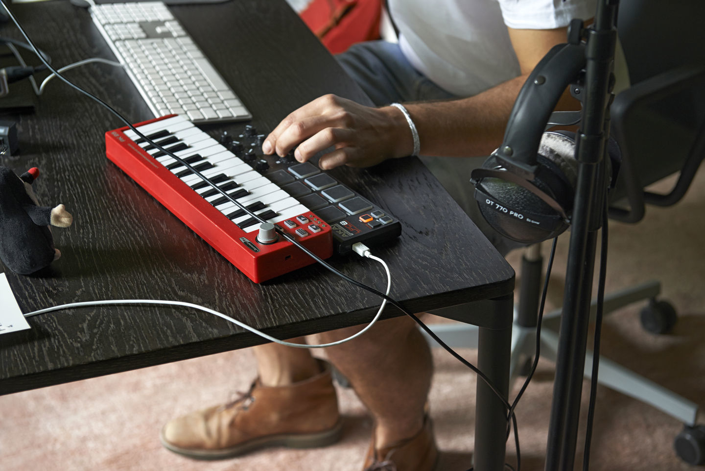 Musiker am Schreibtisch auf Vitra Bürodrehstuhl mit rotem Keyboard, Kopfhörer und Maus.