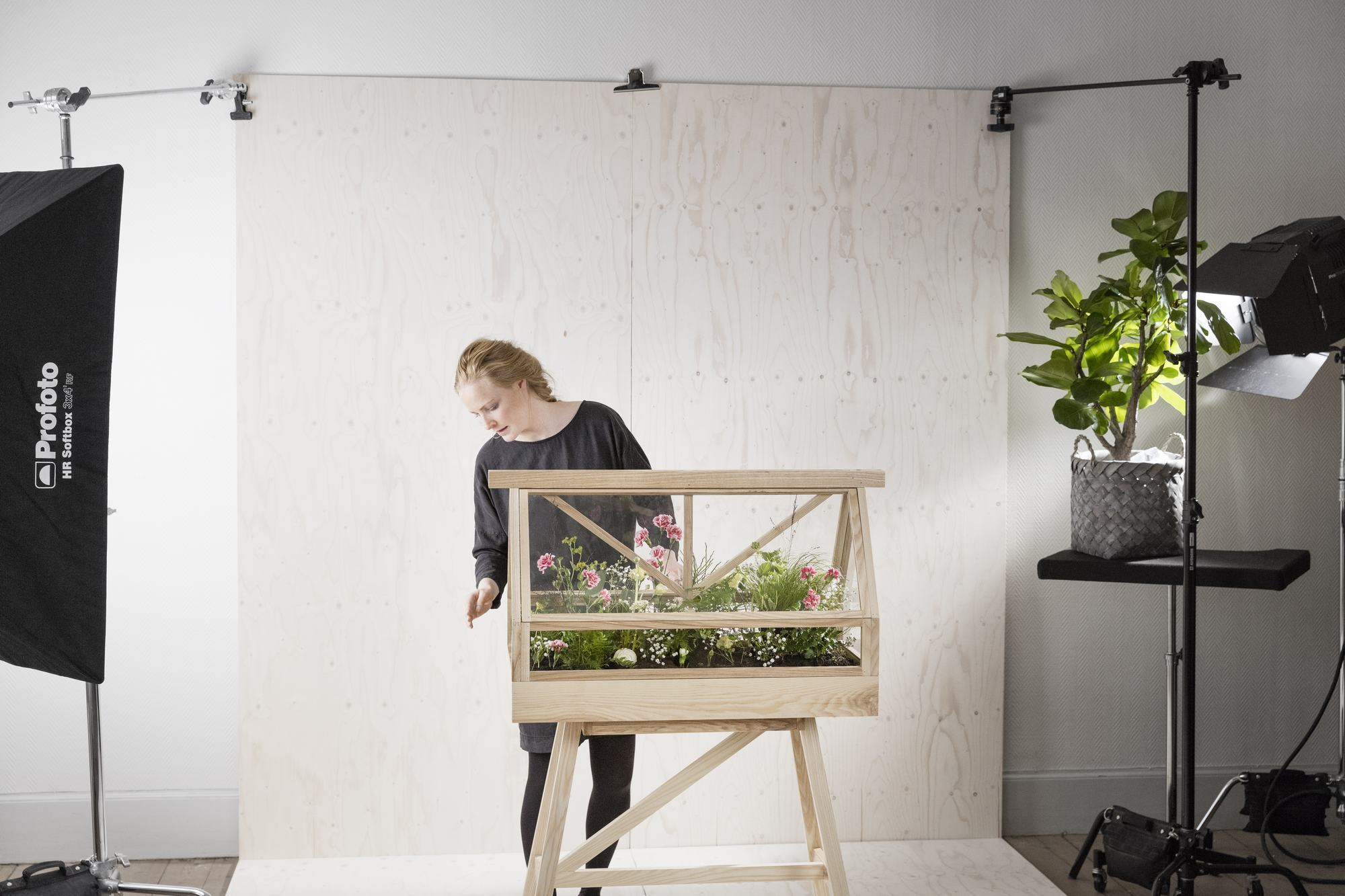Frau betrachtet Greenhouse Gewächshaus von Design House Stockholm mit blühenden Pflanzen.