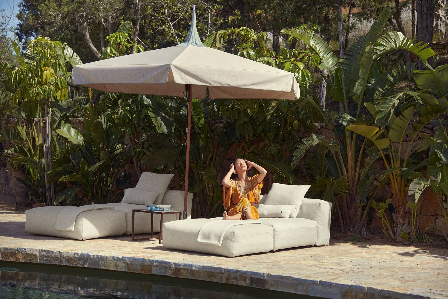 Vetsak Outdoor Sofa Set mit Sonnenschirm und entspannter Frau am Pool im Garten.
