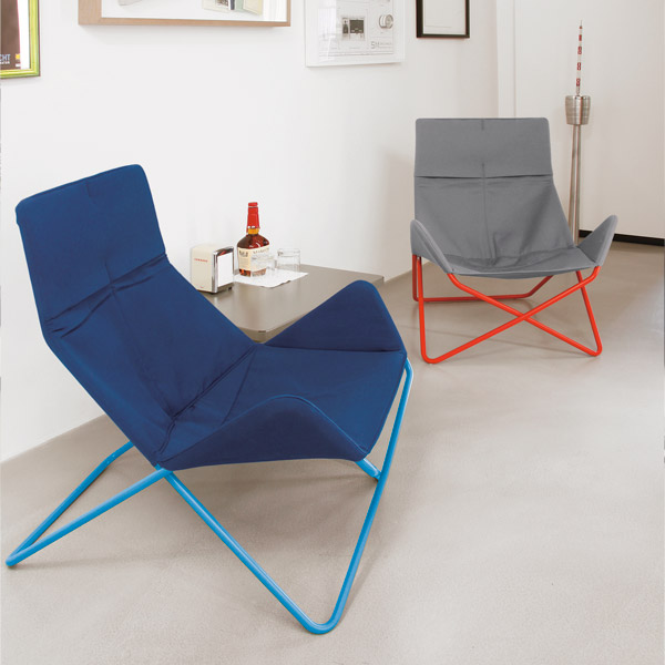 Blauer In-Out Sessel von Richard Lampert und grauer Sessel mit rotem Gestell im modernen Wohnzimmer.