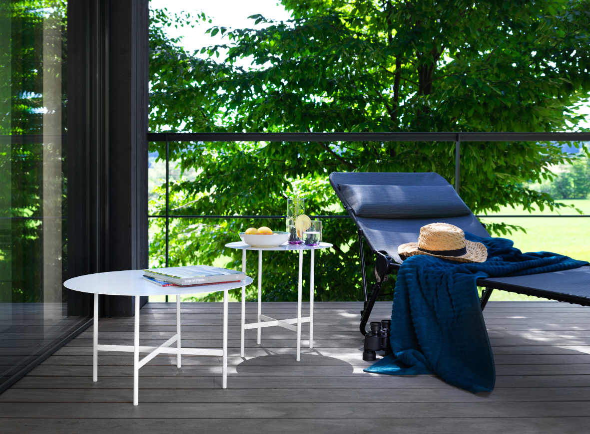 BETA Couchtisch und Beistelltisch von Müller Möbel auf einer Terrasse mit Liege und Ausblick.