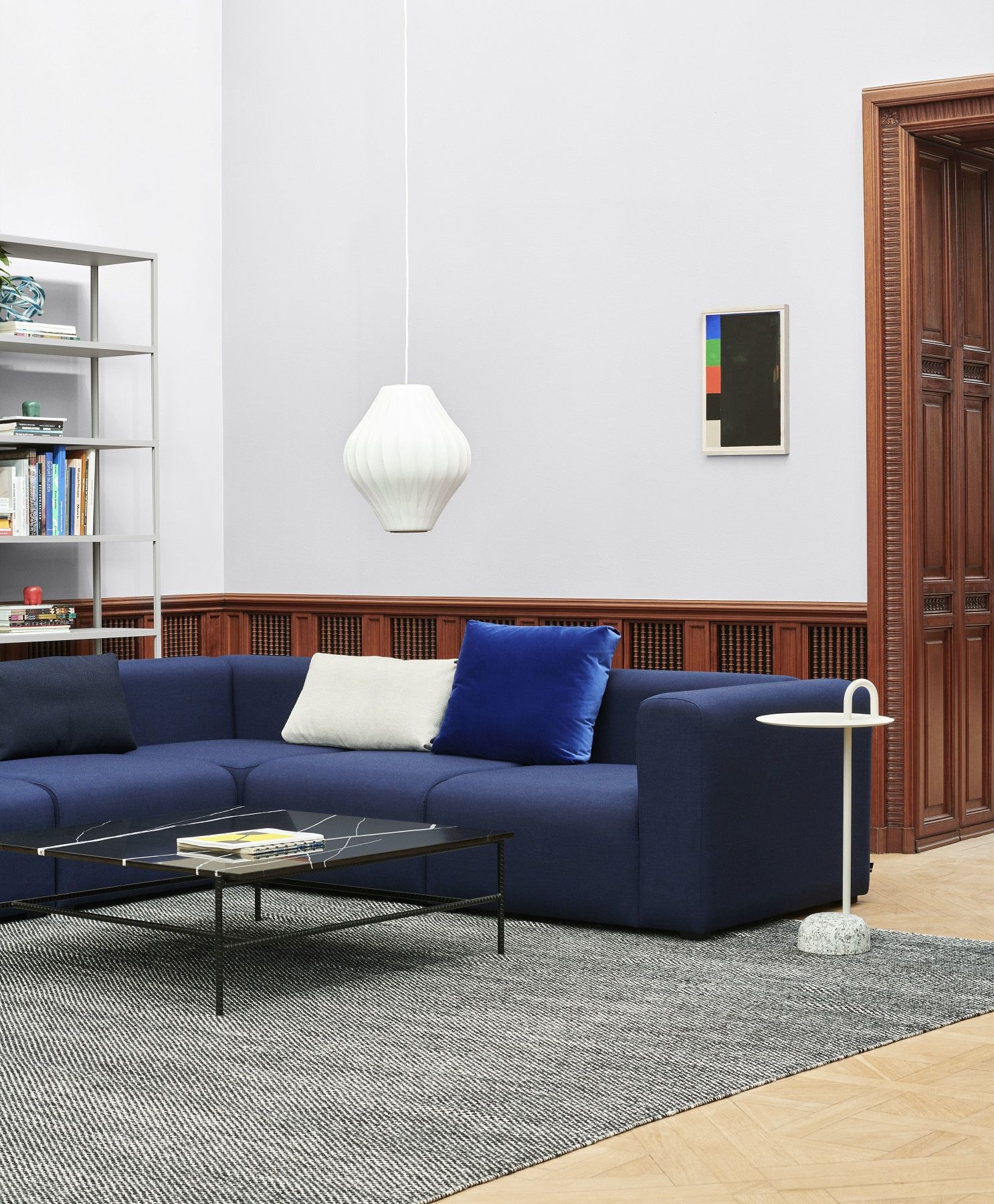 Heller Wohnraum mit blauem Sofa, Couchtisch und weißem Hay Bowler Beistelltisch mit Marmorfuß neben einer Holztür.