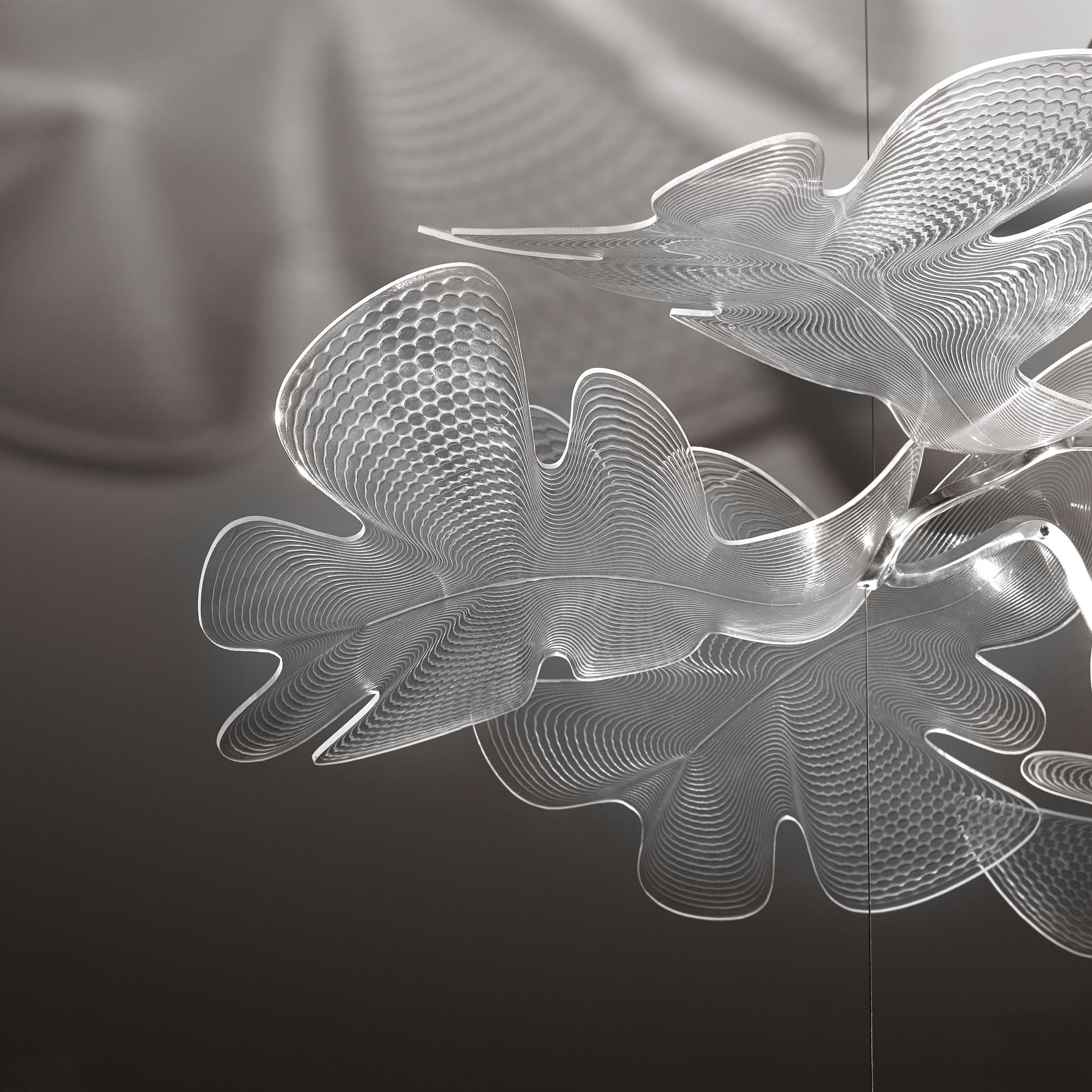 Detailaufnahme der Artemide Chlorophilia Pendelleuchte mit transparentem Diffusor und Chromstruktur. Designlampe für moderne Innenräume.