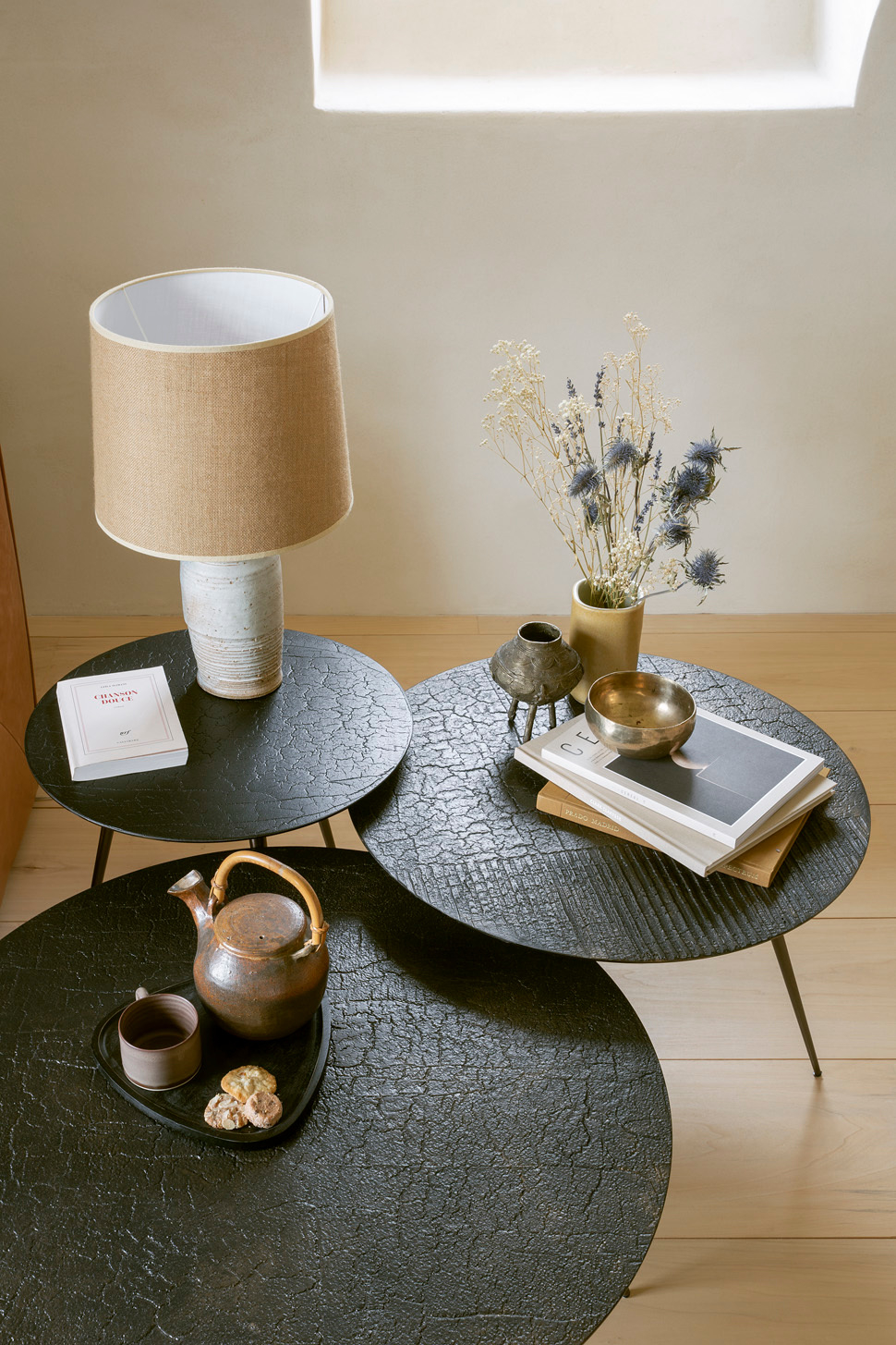 Luna Couchtisch Lava Linear Ethnicraft, drei runde Tische in Schwarz mit Teekanne, Lampe und Dekoration.
