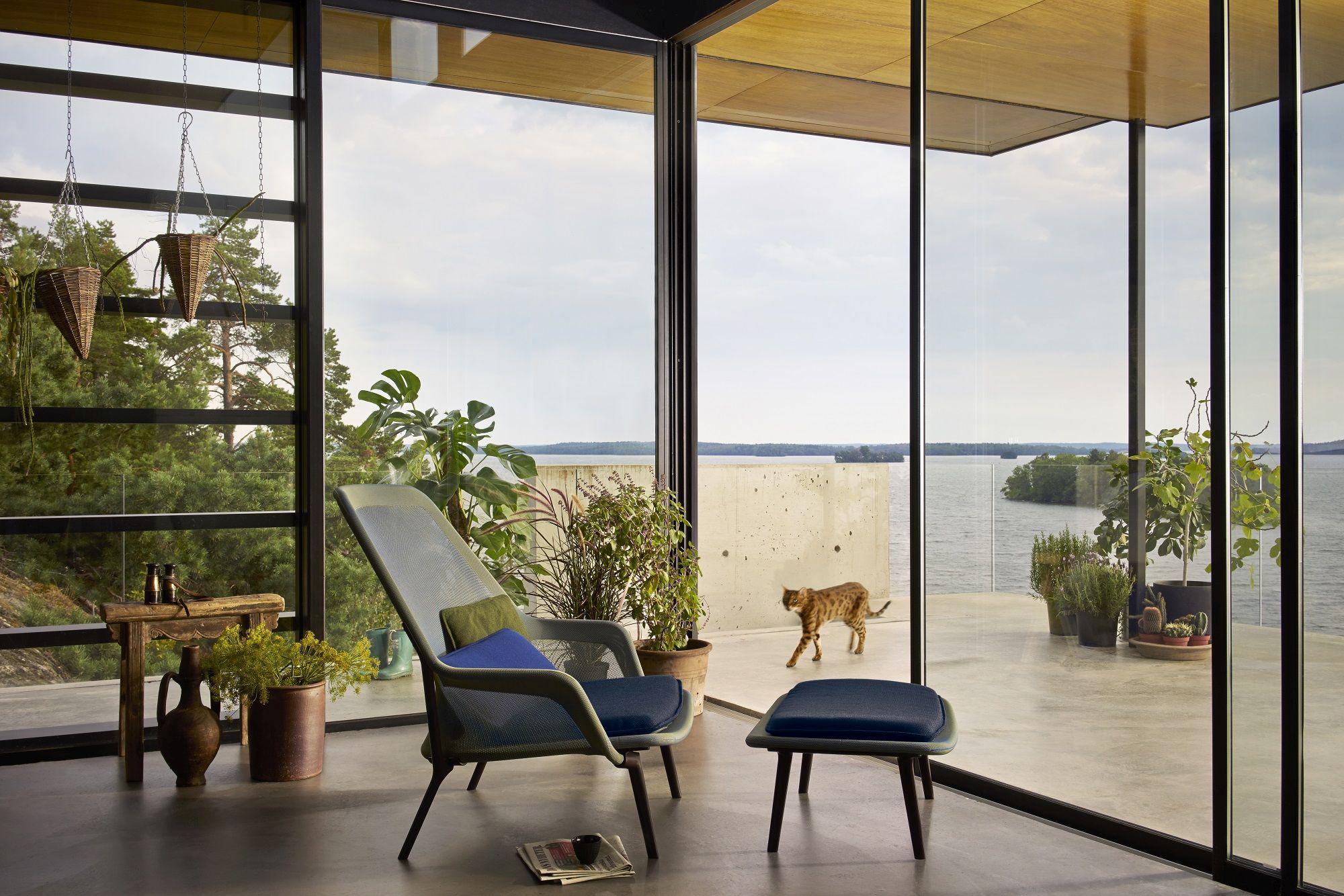 Vitra Slow Chair Sessel mit Hocker in modernem Wohnraum mit Seeblick und Katze.