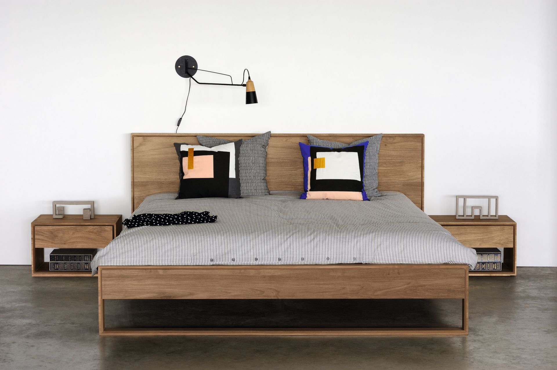Modernes Holzbett mit Nachttischen, gestreifter Bettwäsche und geometrischen Kissen für ein stilvolles Schlafzimmer.