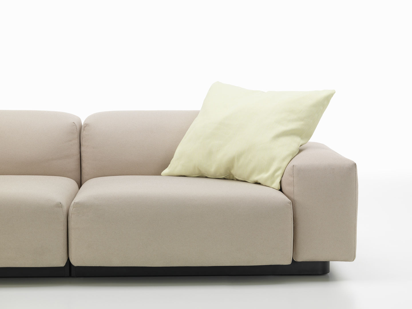 Beiges Sofa mit hellgrünem Vitra Cushions Kissen, modernes Design für Wohnzimmer und stilvolle Dekoration.