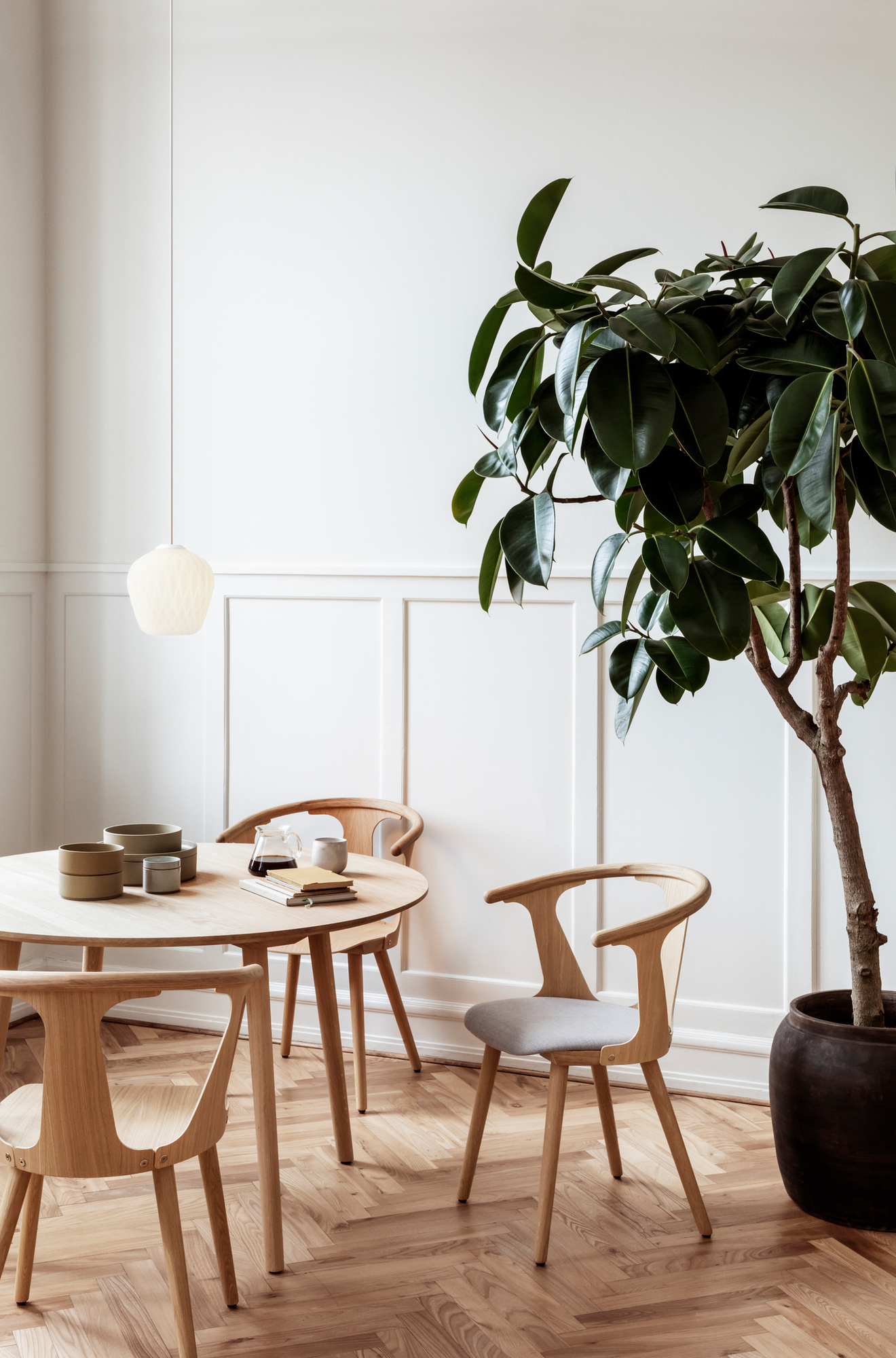 Esszimmer mit AndTradition Blown Pendelleuchte, Holztisch und Stühlen, Zimmerpflanze.