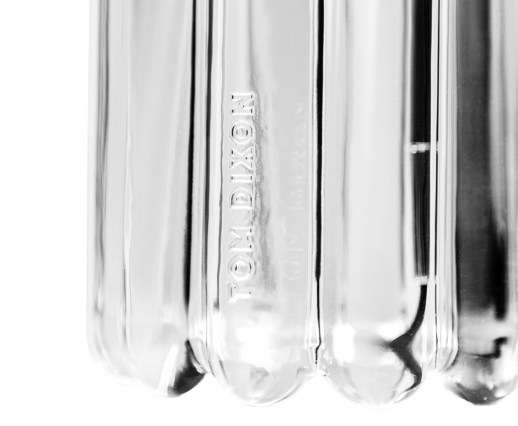 Detailaufnahme der Press Tischleuchte von Tom Dixon, aus klarem, geriffeltem Glas mit eingeprägtem Logo.