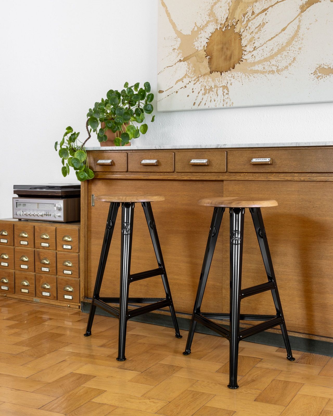 Zwei Rowac Barhocker Model I 75 cm mit schwarzem Gestell und Holzsitz vor Kommode.
