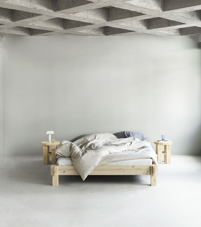 Bett mit zwei Fyr Stool Hockern von Normann Copenhagen als Nachttische in minimalistischem Schlafzimmer.