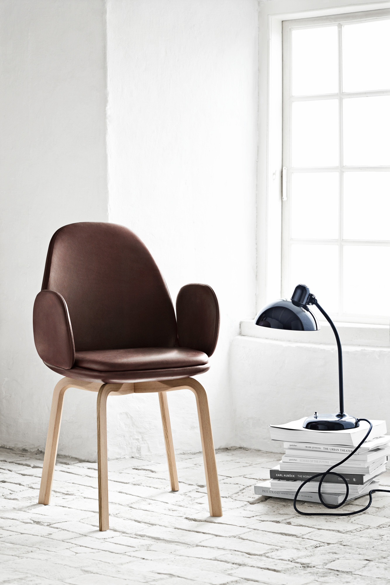 Schwarze KAISER idell 6556 T Tischleuchte von Fritz Hansen neben einem braunen Sessel.