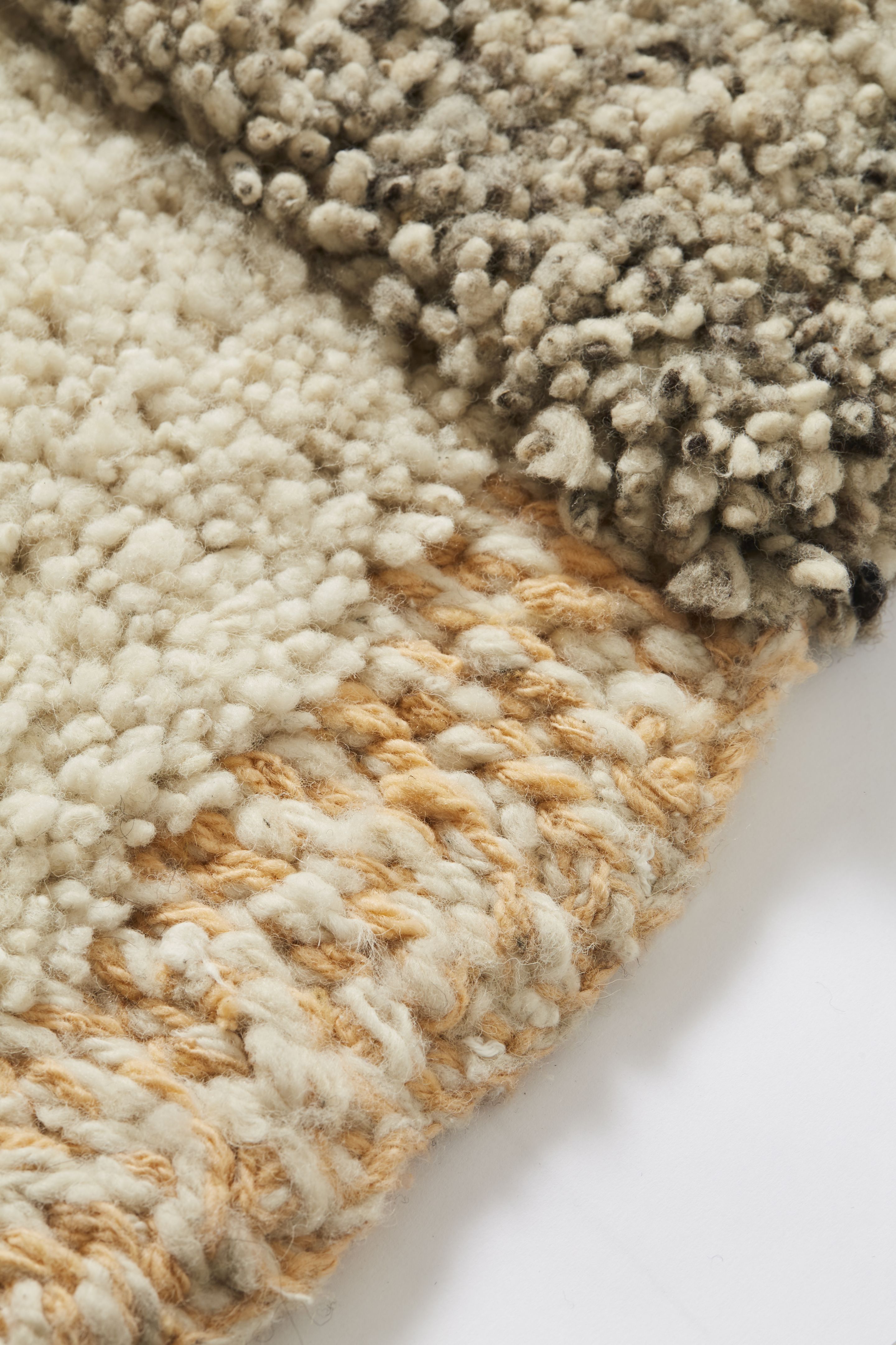 Detailaufnahme des Ames Nudo Teppichs in Beige, Grau und Weiß mit weicher Textur.