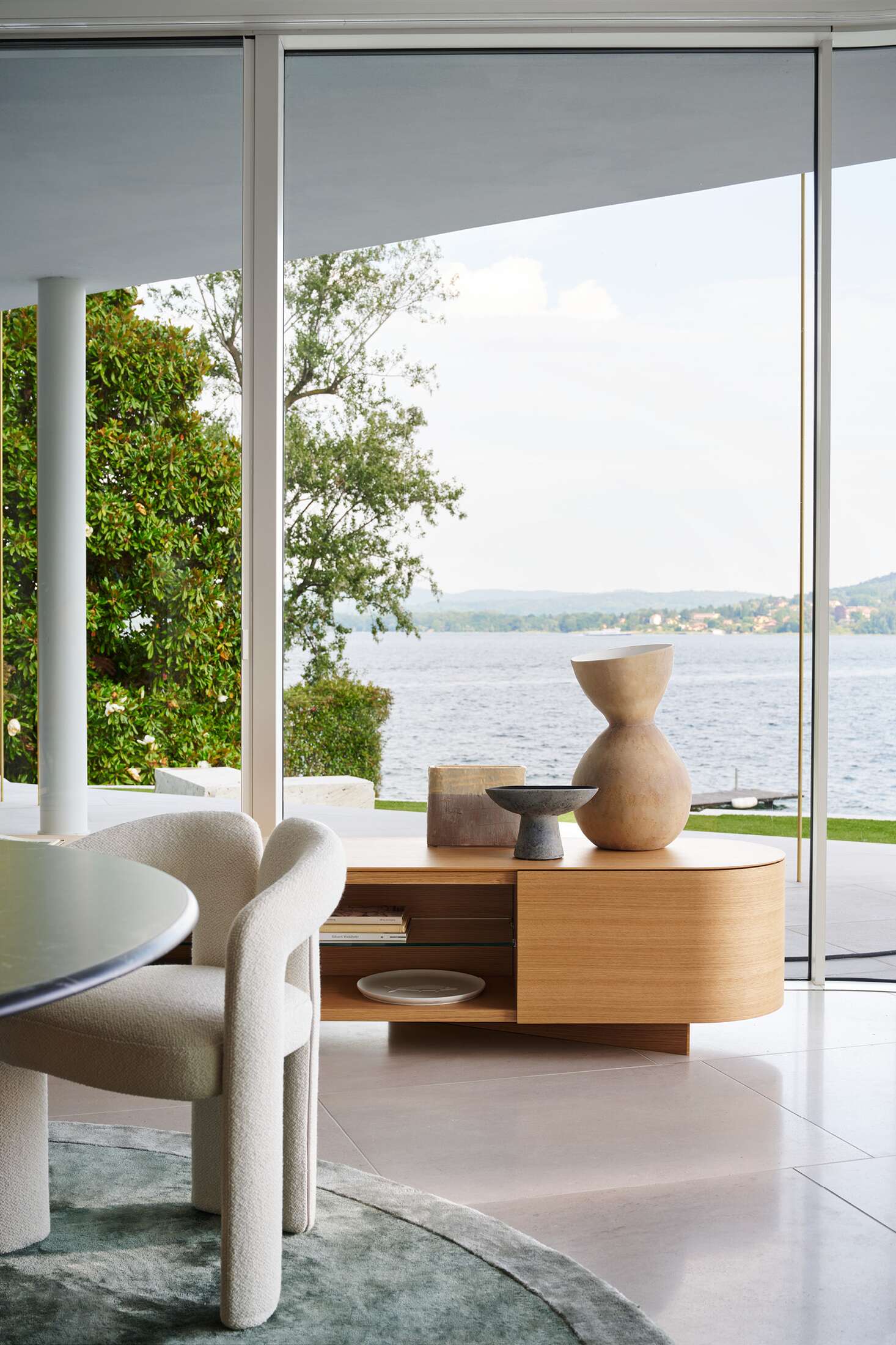 Nahaufnahme des Cassina 562 Dudet Sessels in einem hellen Wohnraum mit Seeblick.