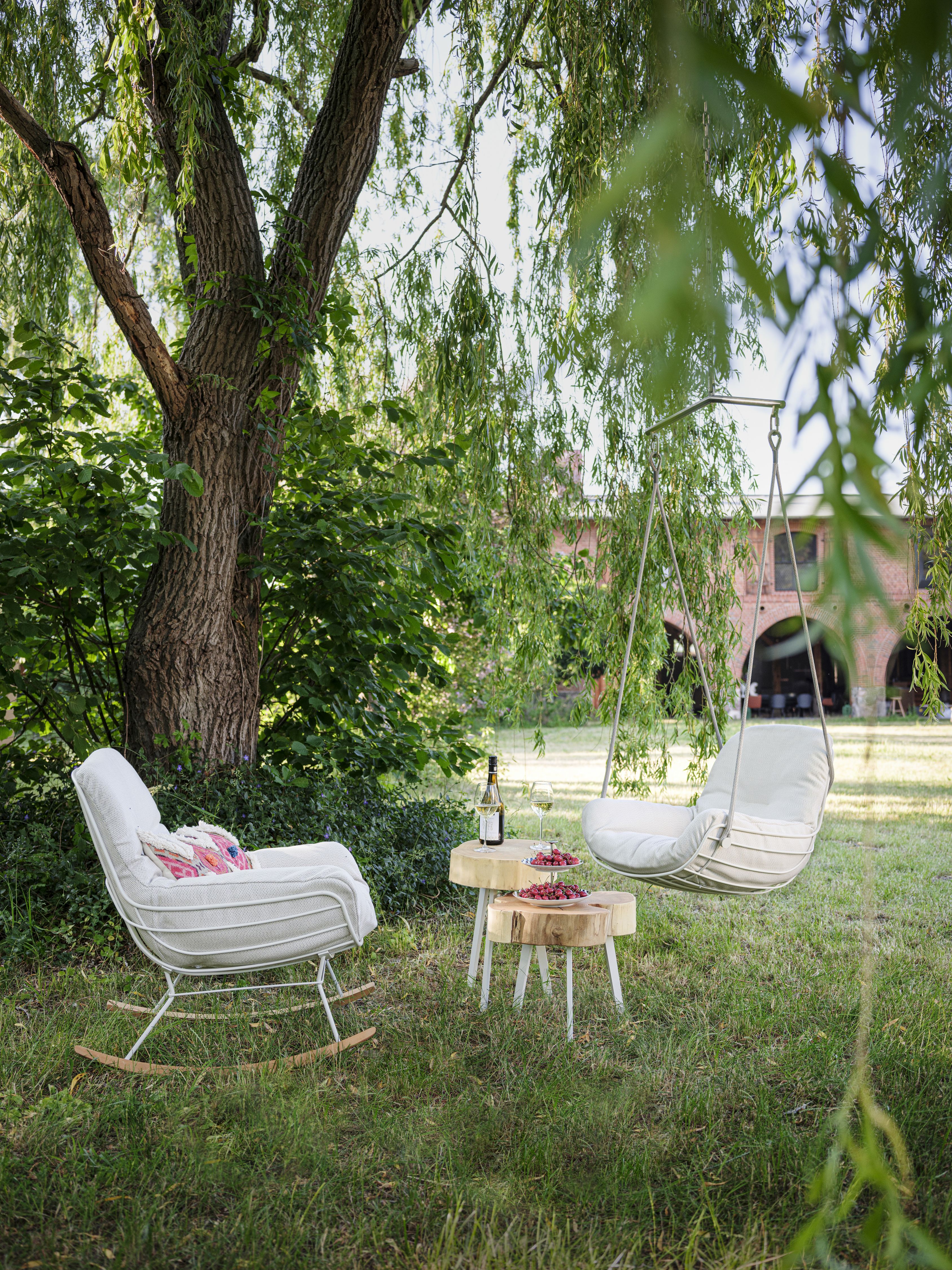 Leyasol Lounge Schwingsessel und Schaukelstuhl im Garten mit Getränken für entspannte Stunden im Freien.