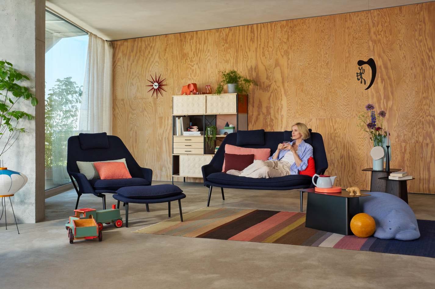 Vitra Slow Chair Sessel mit Stoffbezug in blau, kombiniert mit passendem Hocker in modernem Wohnzimmer.