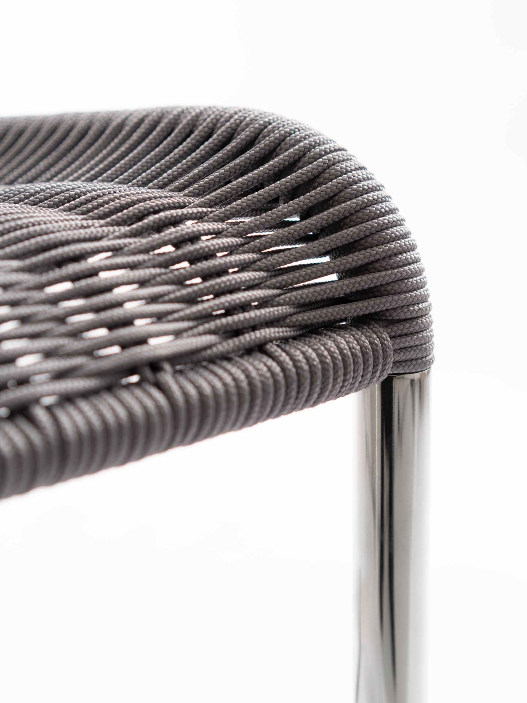 Detailaufnahme: Grauer B20 Kragstuhl von Tecta mit geflochtener Sitzfläche und Stahlrohrgestell. Modernes Möbeldesign.
