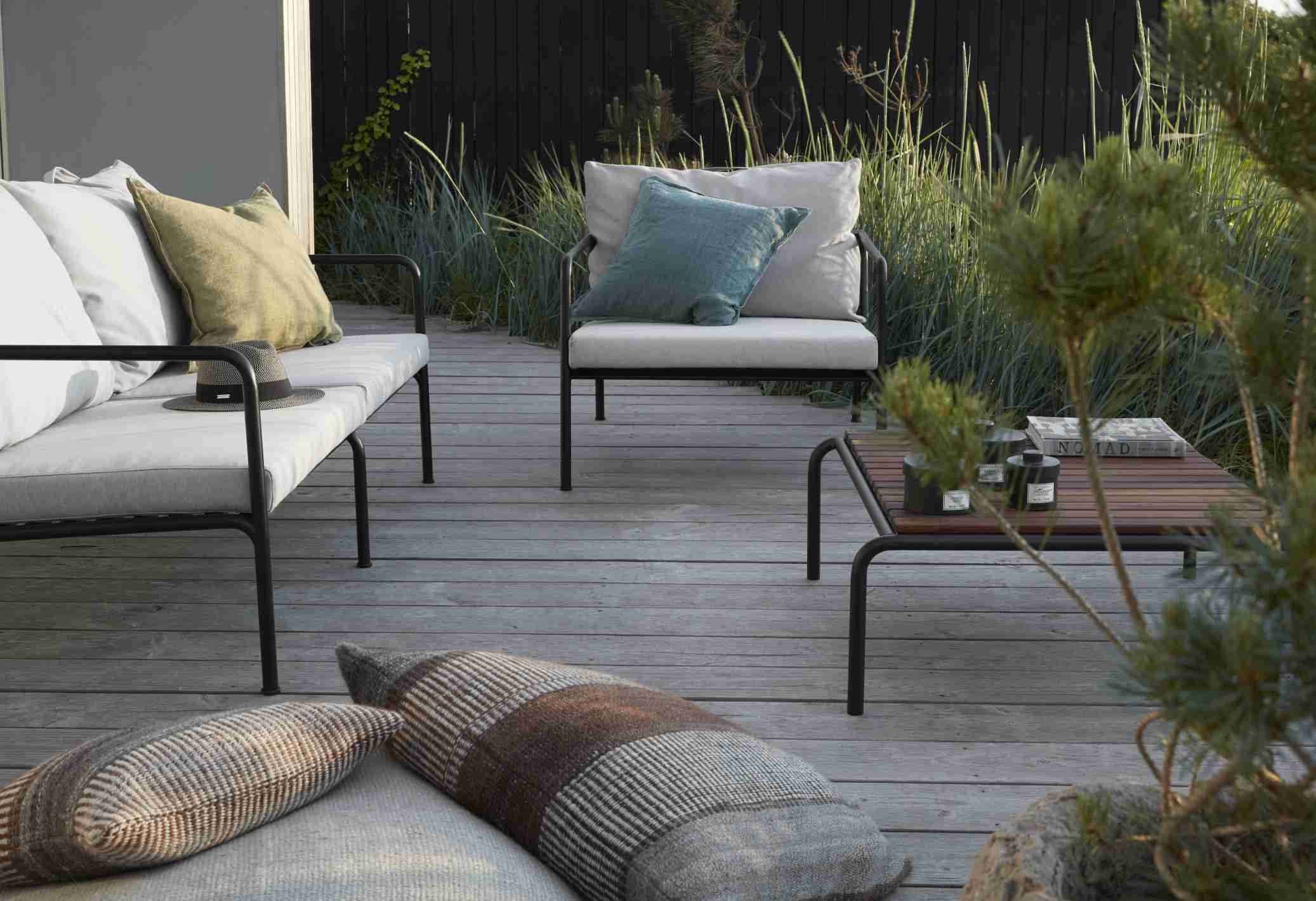 Avon Lounge Chair Outdoor Sessel von Houe auf einer Terrasse mit Kissen und Tisch.