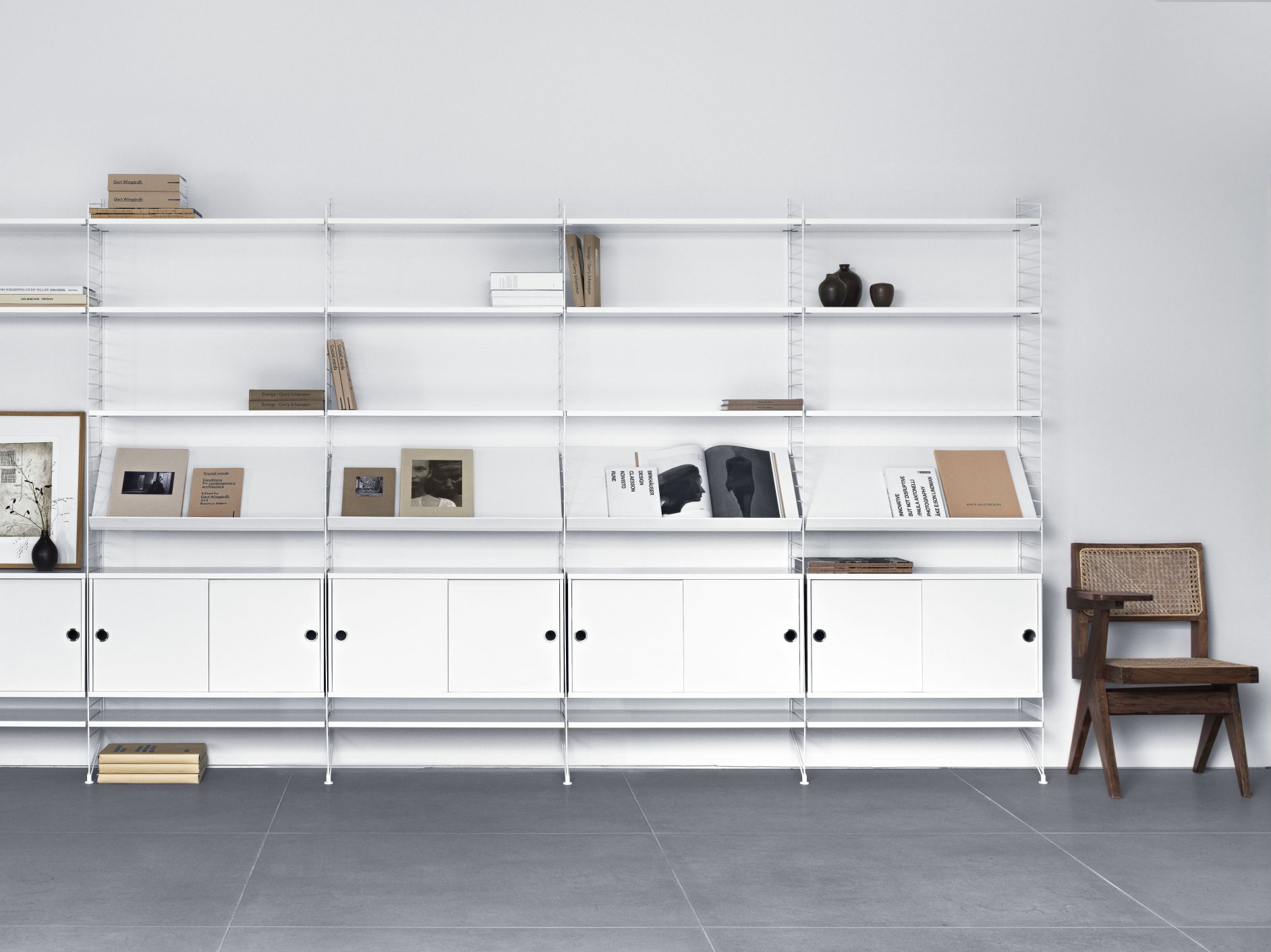 Weißes String Regal mit Schränken und Regalböden, Bücher und Deko, skandinavisches Design.
