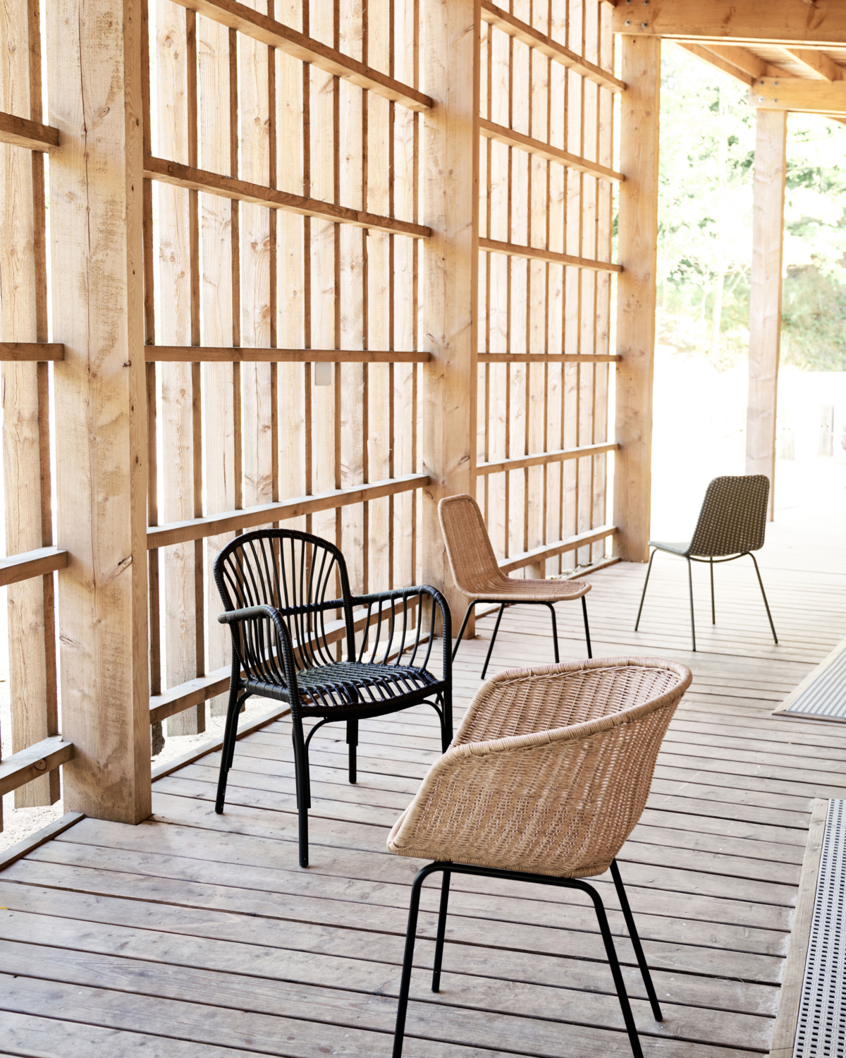 HDHapur Stühle von House Doctor auf einer Holzveranda, verschiedene Designs und Farben, Indoor/Outdoor geeignet.