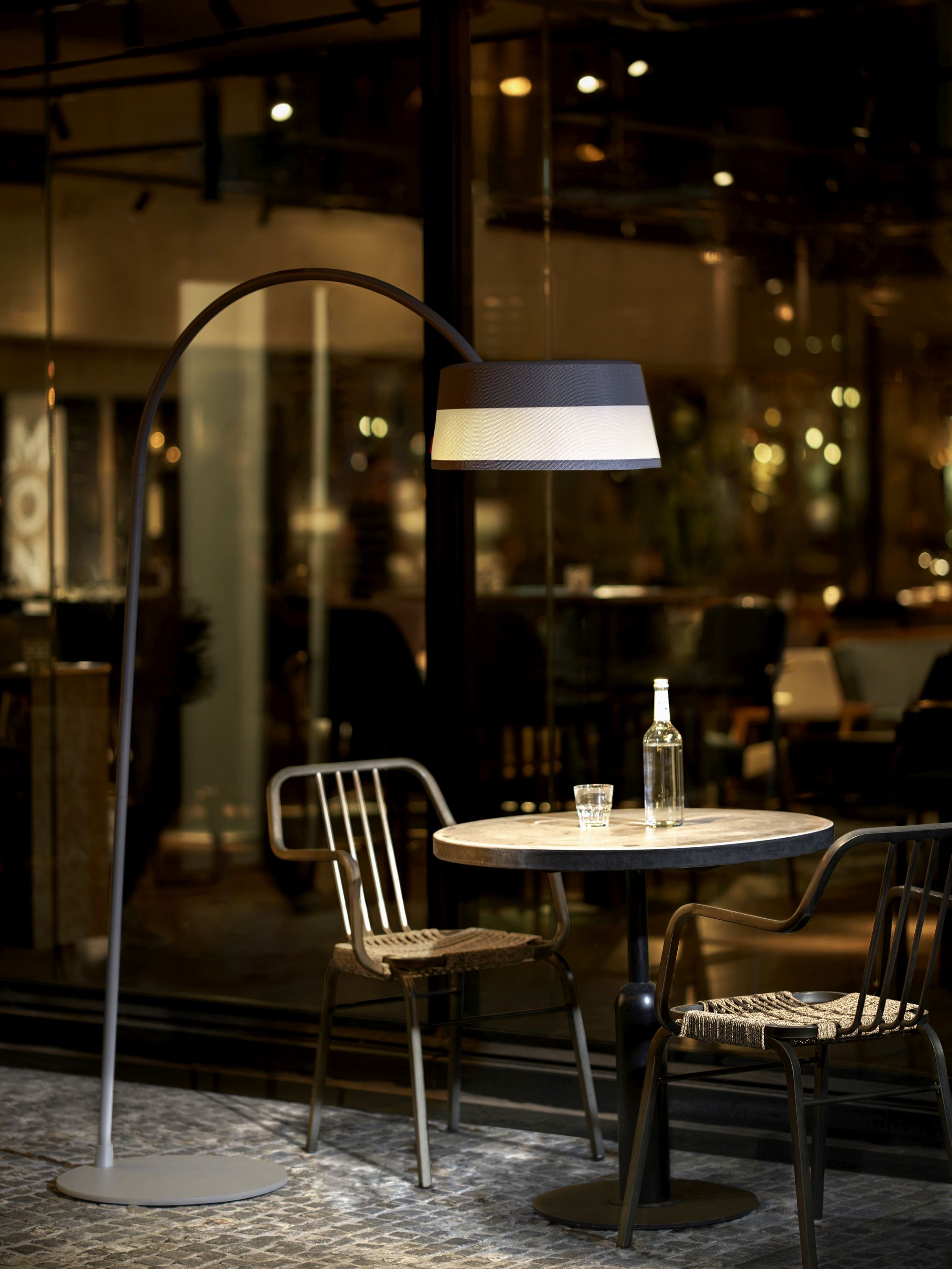 ISA-BELLE Solarleuchte als Bogenlampe über Tisch mit Stühlen, stimmungsvolle Gartenbeleuchtung für den Außenbereich.