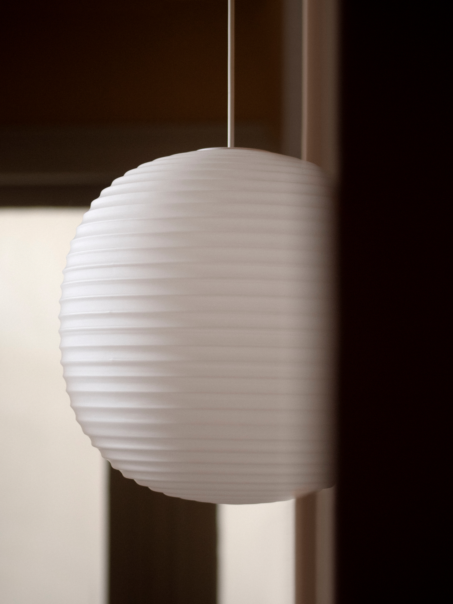 Nahaufnahme der weißen Lantern Pendelleuchte von New Works mit horizontalen Rillen.