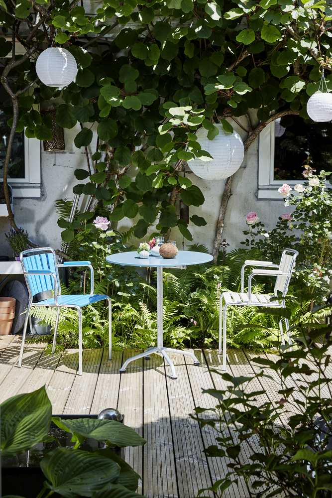 Blauer Haefeli Gartentisch Outdoor Ø 60 cm mit zwei Stühlen auf einer Holzterrasse.