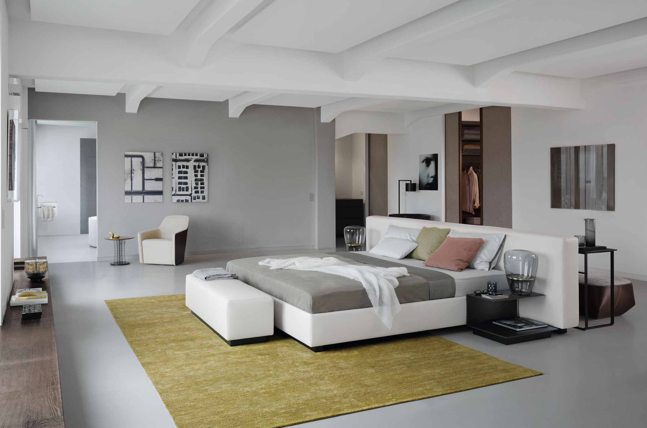 Heller Raum mit modernem Bett, Sessel und Teppich. Walter Knoll Sessel im Hintergrund sichtbar.