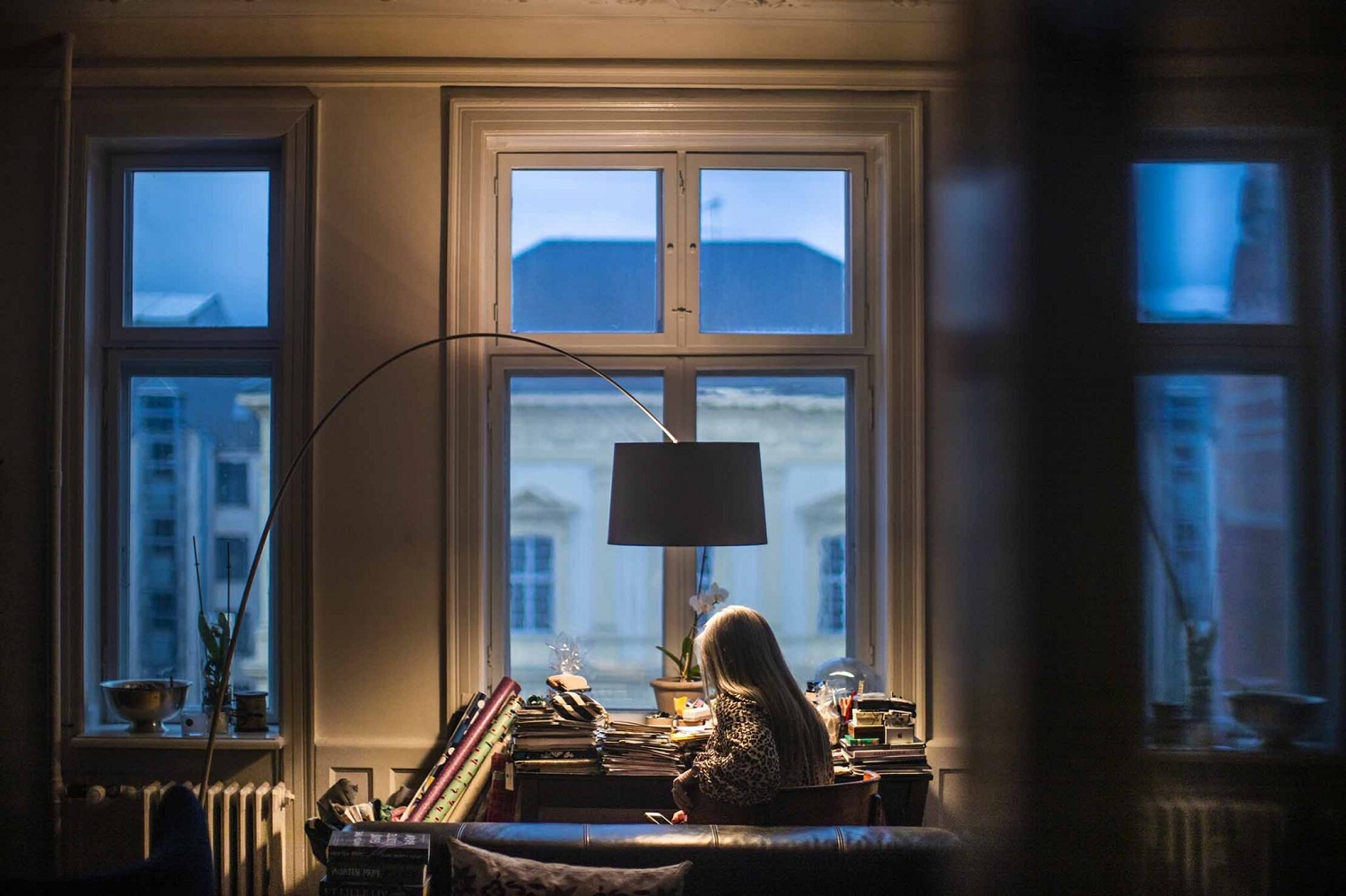 Frau am Schreibtisch unter der Foscarini Twiggy Stehleuchte, die ein warmes Licht in den Raum wirft.