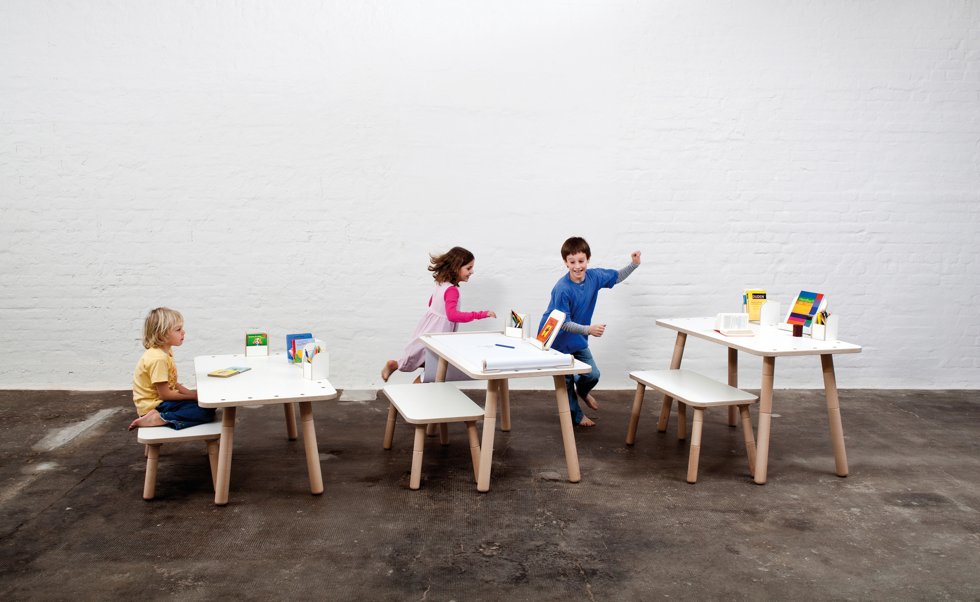 Growing Table Kindersitzgruppe: Kinder spielen an weißen Kindertischen und Stühlen der Marke Pure Position.