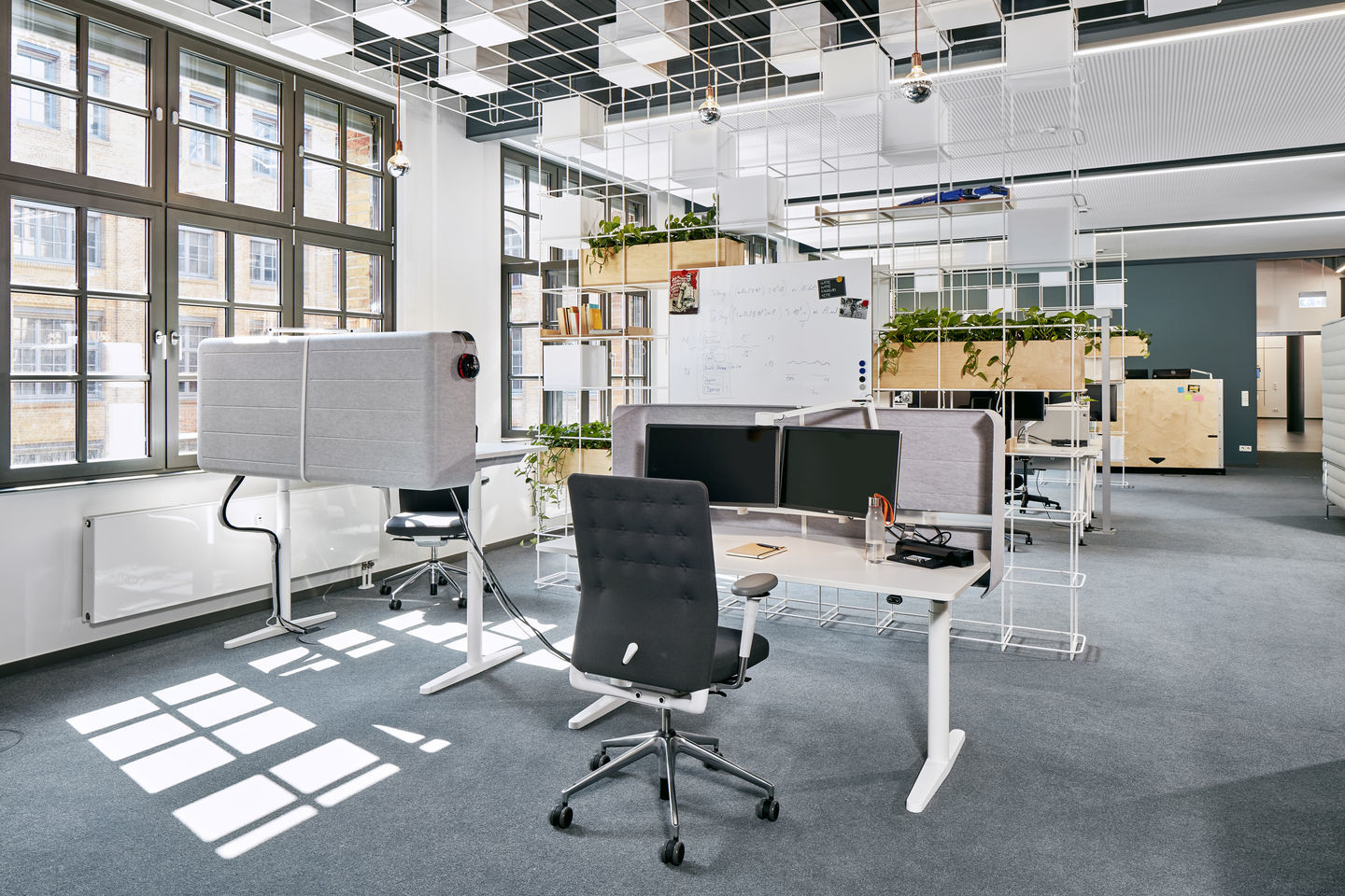 Moderner Büroraum mit Vitra ID Chair Bürodrehstuhl, höhenverstellbaren Schreibtischen und akustischen Trennwänden für konzentriertes Arbeiten.