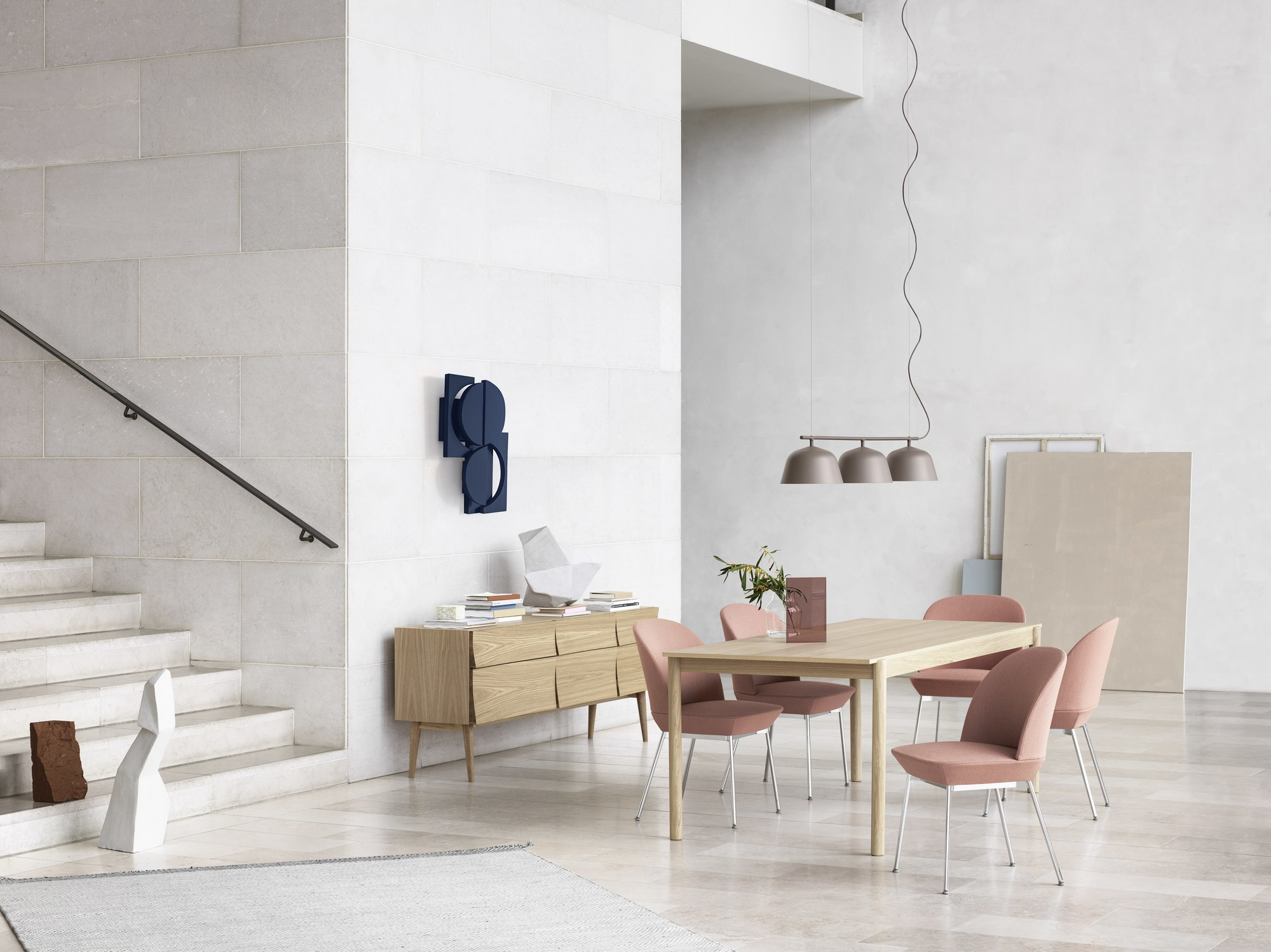 Helles Wohnzimmer mit Muuto Sideboard aus Eichenholz, Esstisch und rosafarbenen Stühlen.