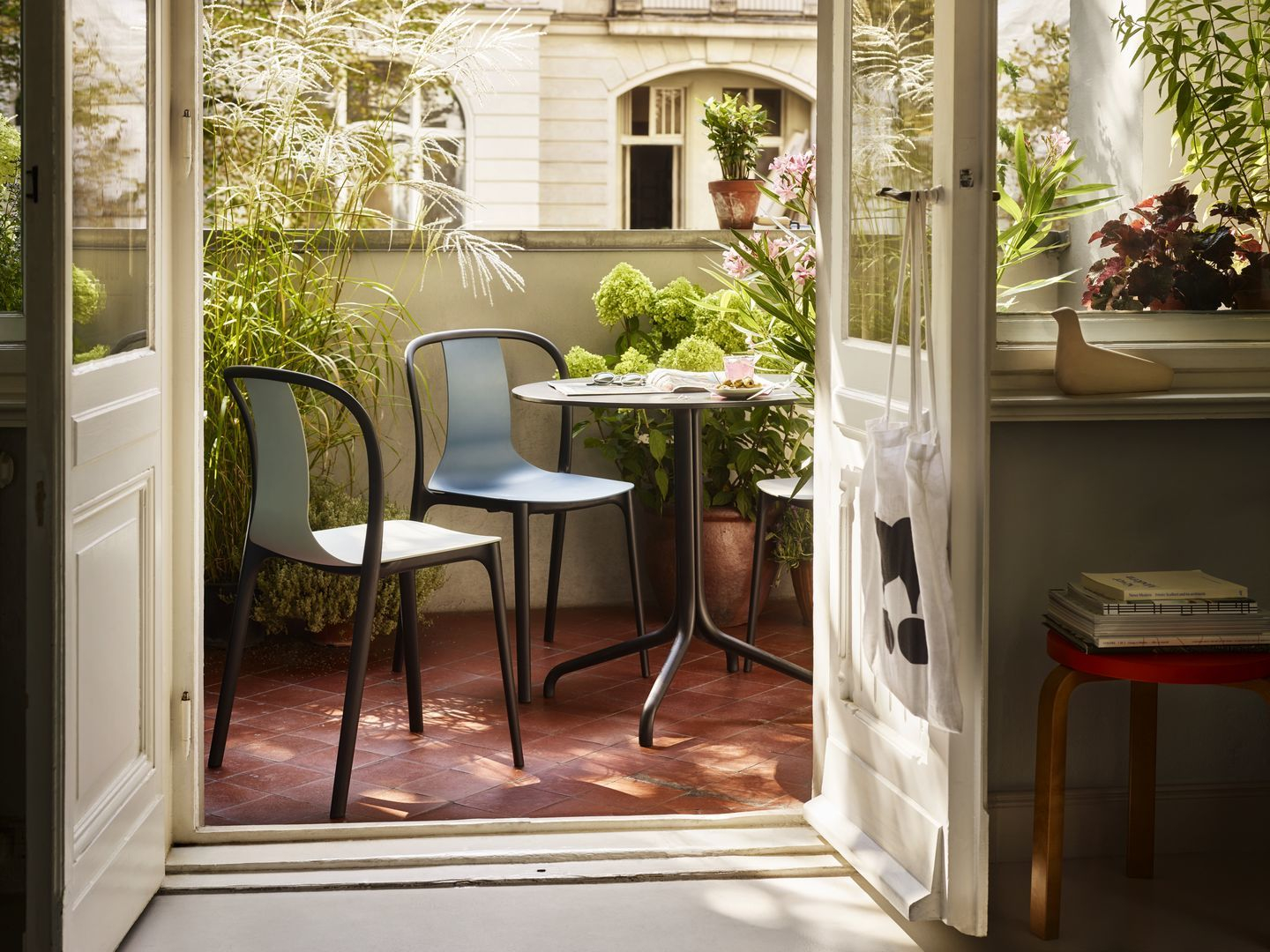 Balkon mit zwei Vitra Belleville Armchair Plastic Stühlen in Blau und Weiß an kleinem Tisch.