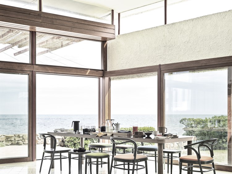 Esstisch mit Beaulieu Stühlen von Wiener GTV Design vor Panoramafenster mit Meerblick.