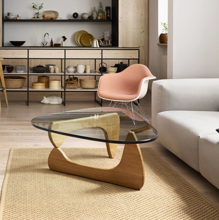 Moderner Dreieck-Couchtisch mit Glasplatte und Holzfuß auf einem Teppich im Wohnzimmer. Design Möbel für stilvolles Wohnen.