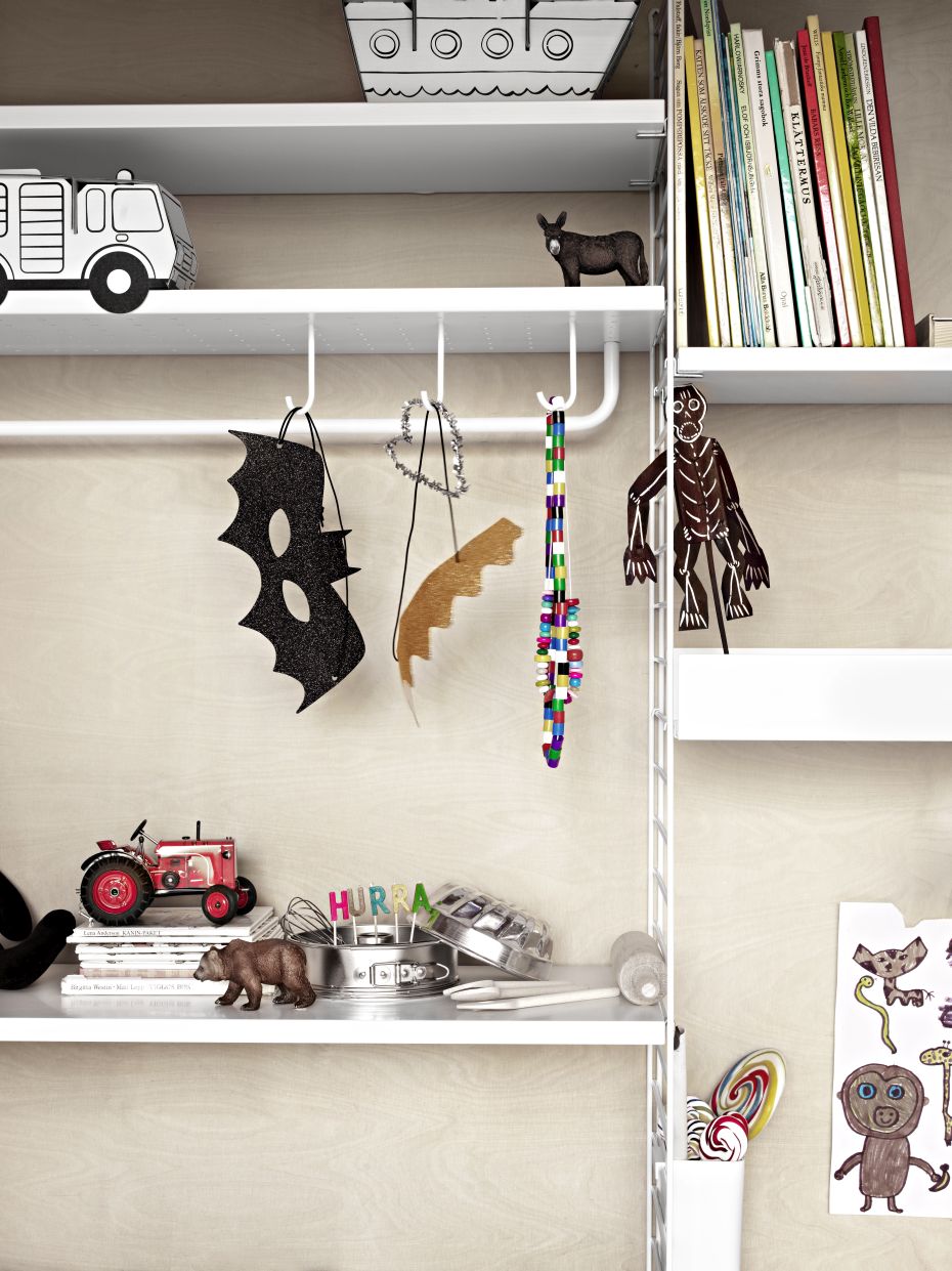 Detailaufnahme: String Furniture Regalboden aus Metall, schwarz, mit Spielzeug und Kinderbüchern dekoriert.
