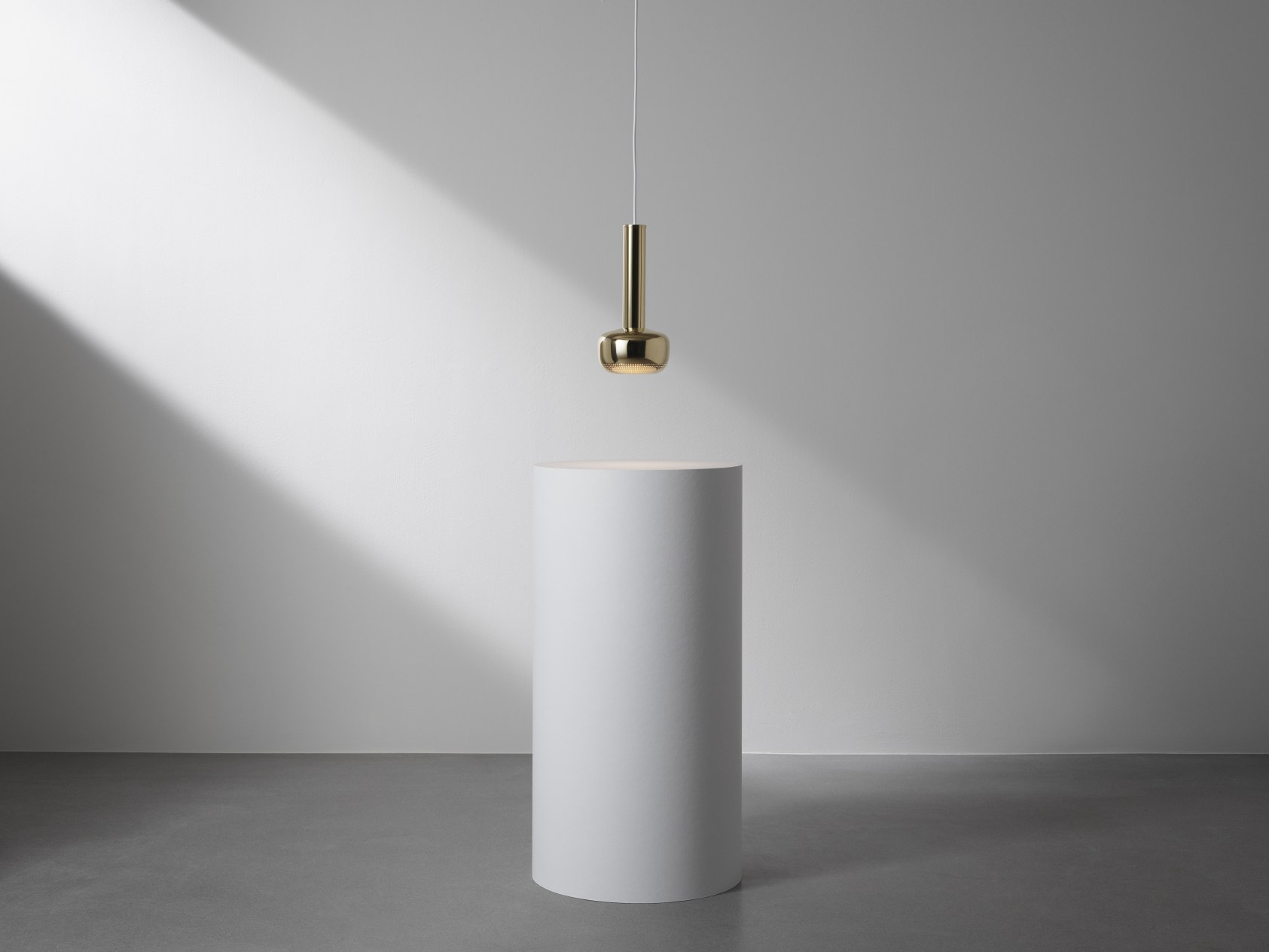 Nahaufnahme der goldenen VL 56 Pendelleuchte von Louis Poulsen über einem weißen Sockel, modernes Design.