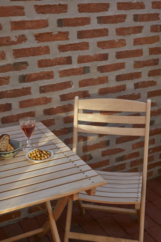 Selandia Stuhl von Skagerak by Fritz Hansen aus Holz mit Tisch und Snacks im Freien.