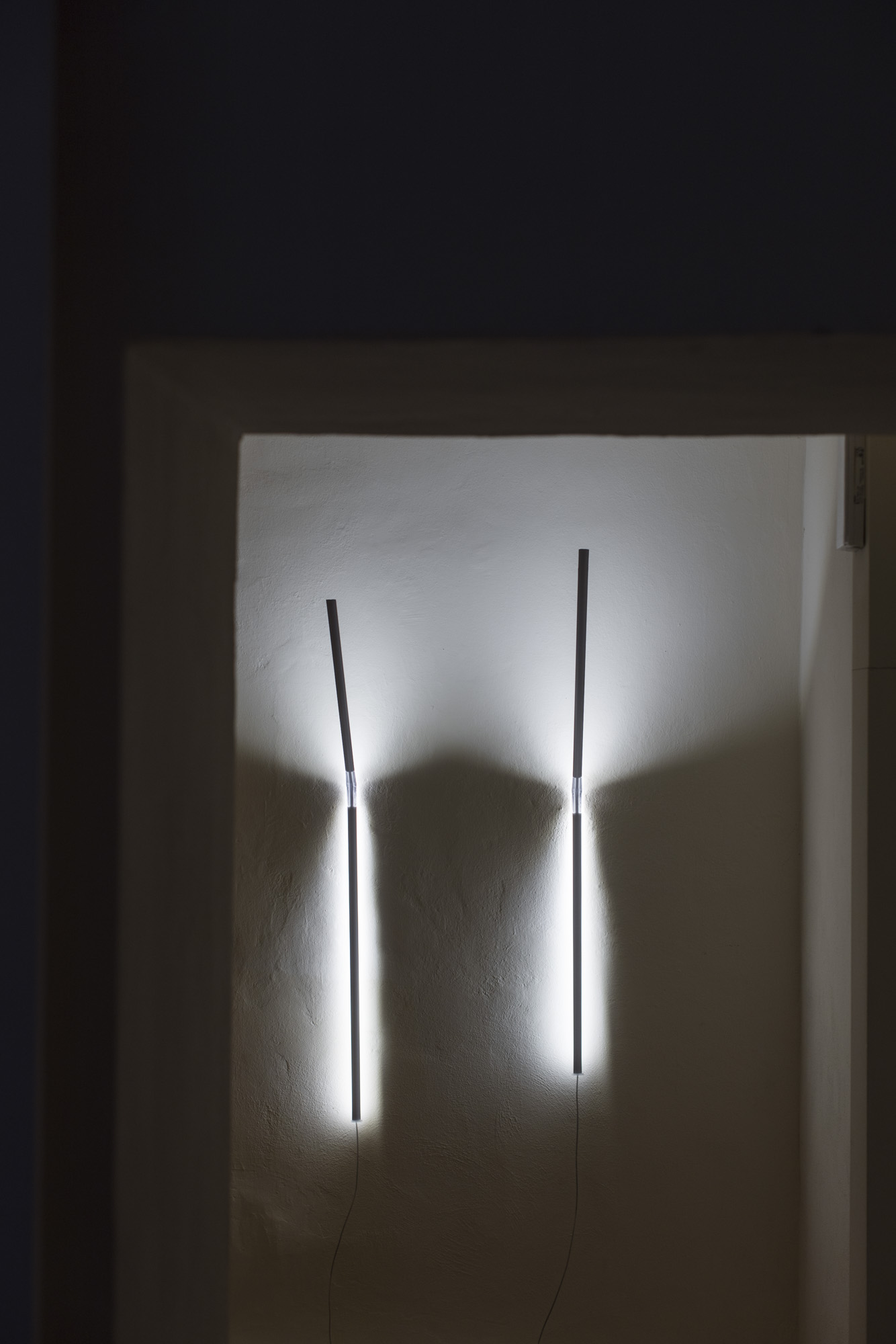 Zwei minimalistische Measure Light Wandleuchten von Ingo Maurer an einer weißen Wand, indirekte Beleuchtung.