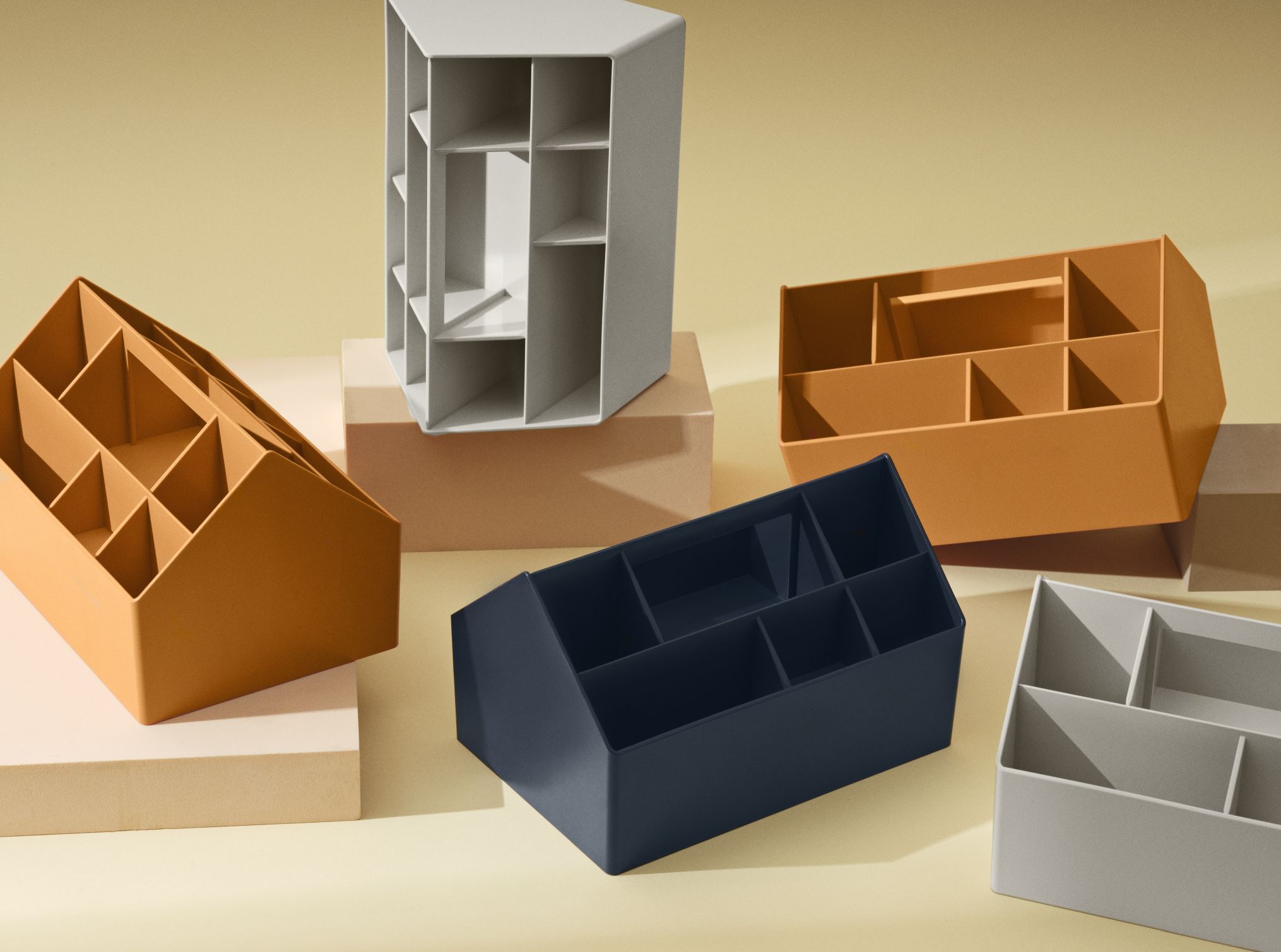 Mehrere Muuto Sketch Toolbox Organisationsboxen in verschiedenen Farben auf beigem Hintergrund.