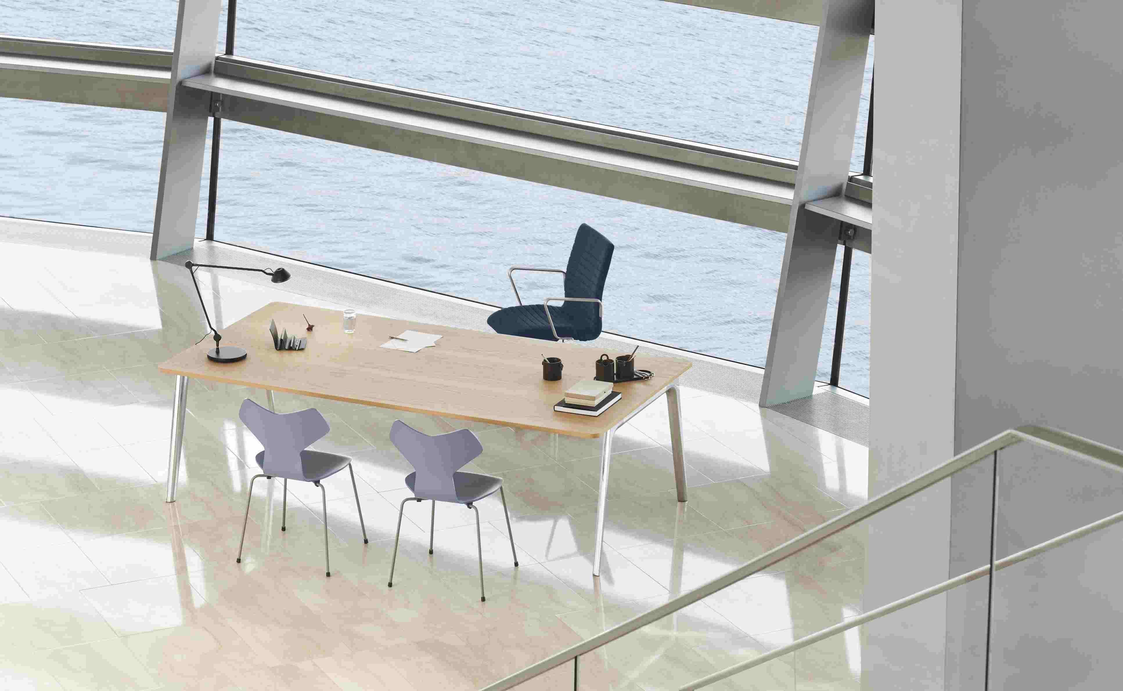 Büro mit Schreibtisch, Grand Prix Stühlen von Fritz Hansen und Bürostuhl vor Fenster mit Meerblick.