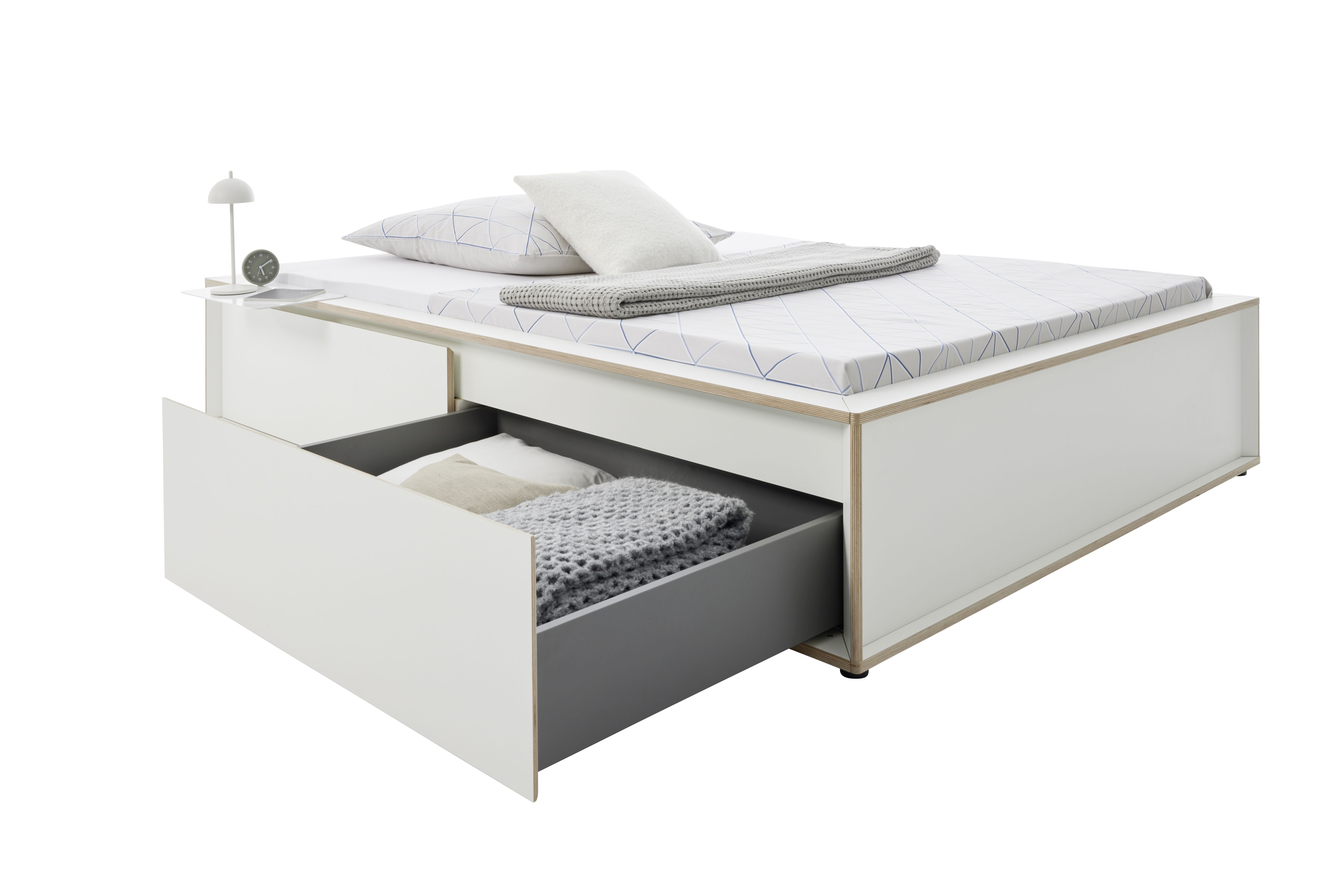 Spaze Bett von Müller Möbelwerkstätten in Weiß mit Schublade, Nachttisch, Lampe und Textilien.