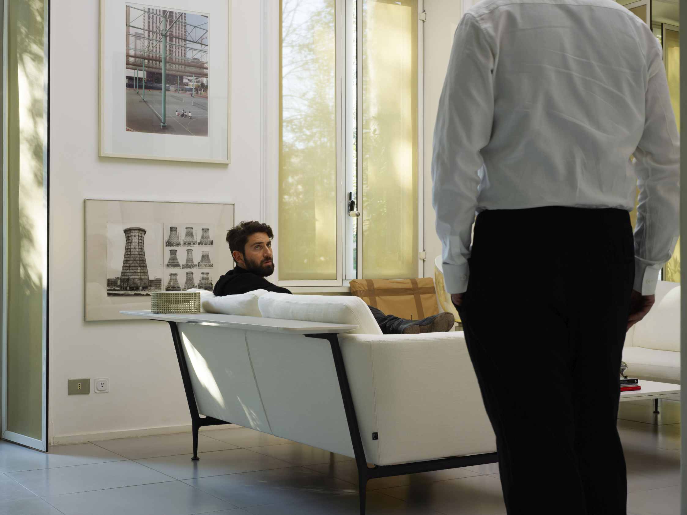 Mann entspannt auf einem weißen Suita 2-Sitzer Sofa von Vitra im modernen Wohnzimmer mit Tageslicht.